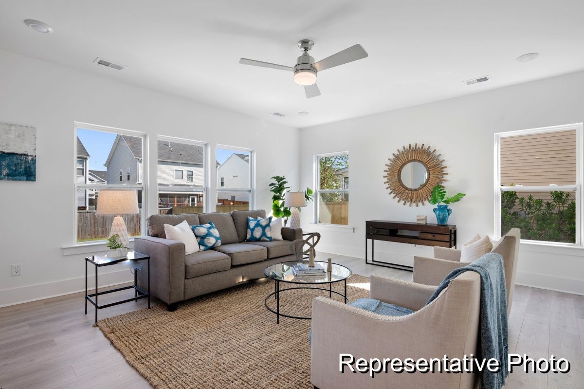 A living room with a couch , chairs , and a ceiling fan.