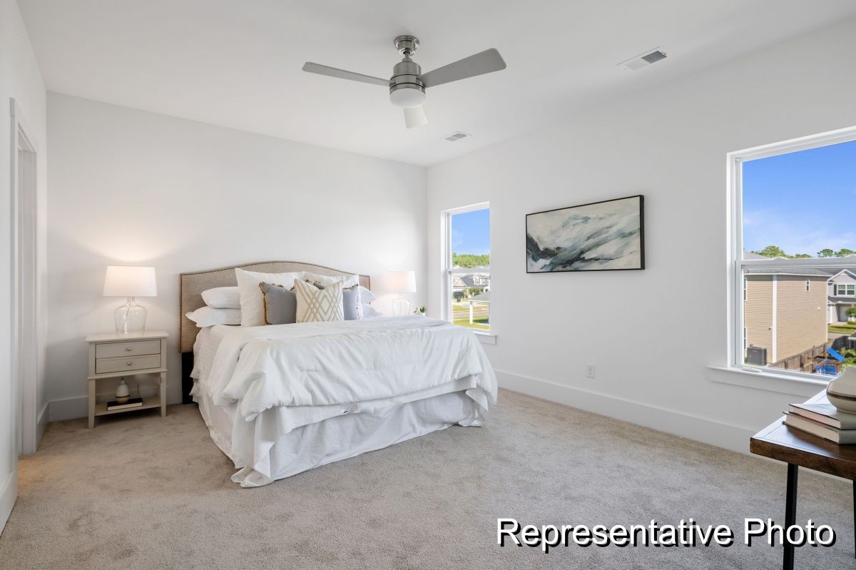 A bedroom with a bed , nightstand , ceiling fan and window.