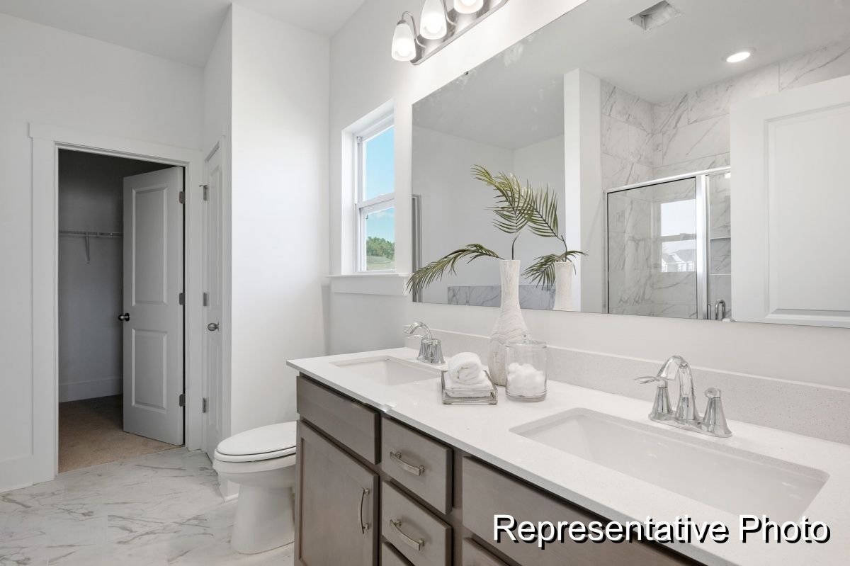 A bathroom with two sinks , a toilet , and a large mirror.