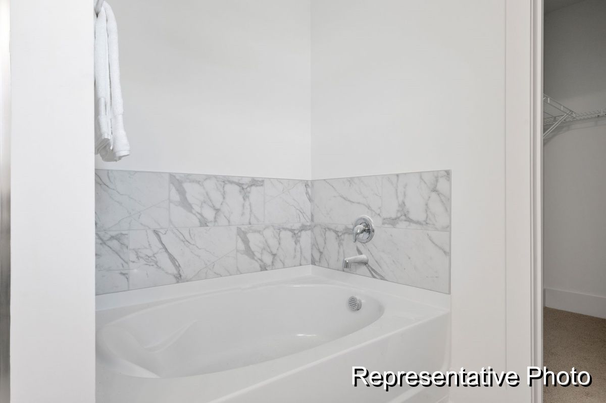 A bathroom with a bathtub and a marble wall.