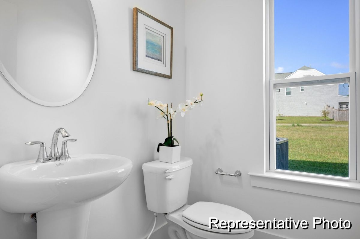 A bathroom with a sink , toilet , mirror and window.