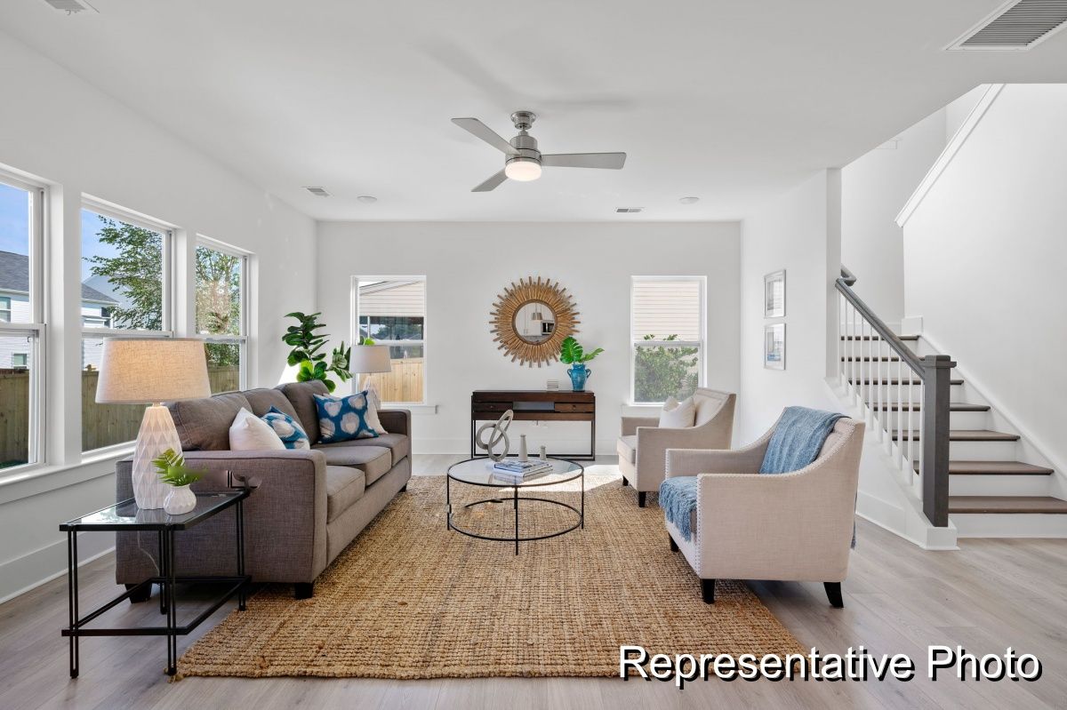 A living room with a couch , chairs , and a ceiling fan.