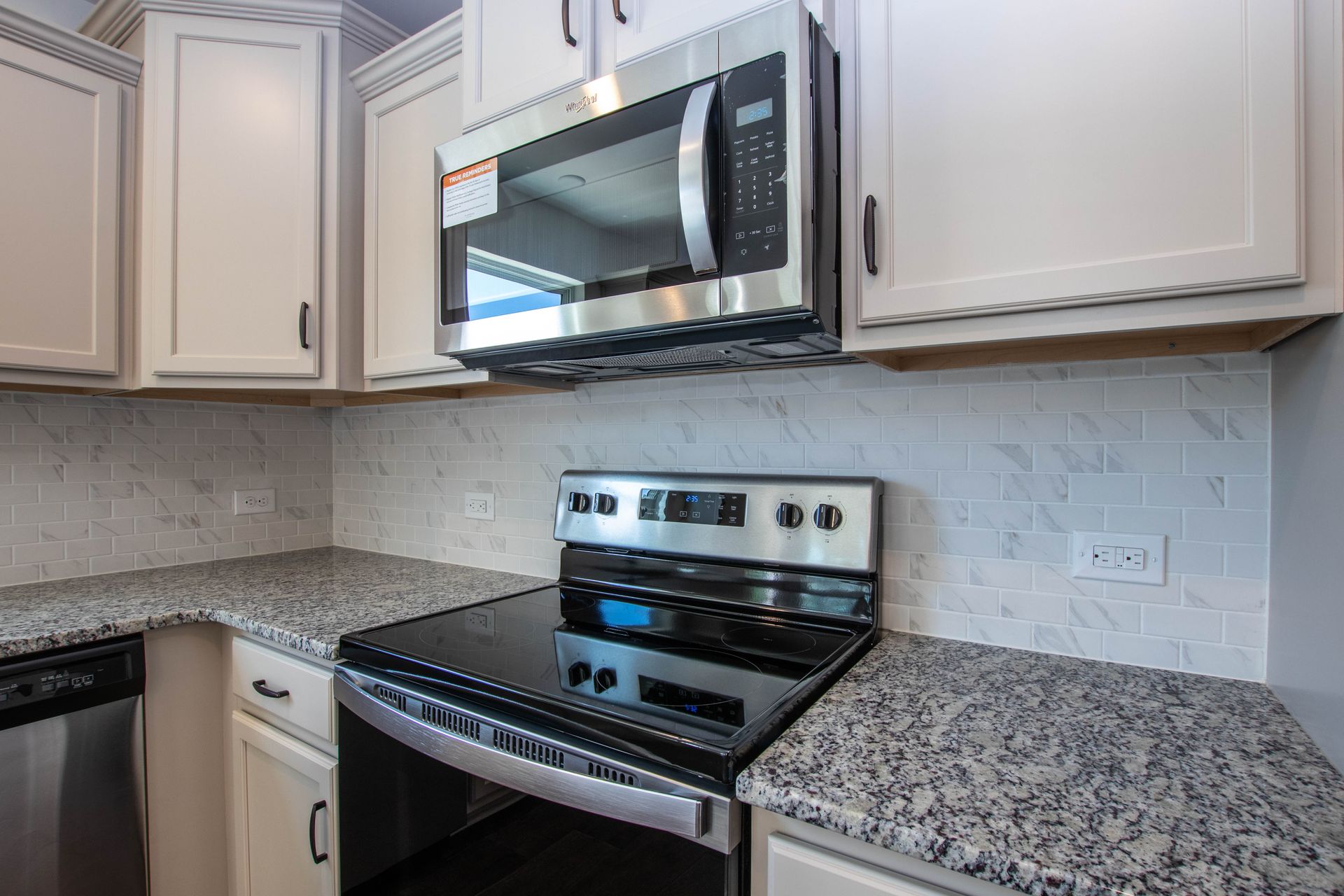 A kitchen with granite counter tops , stainless steel appliances , and white cabinets.