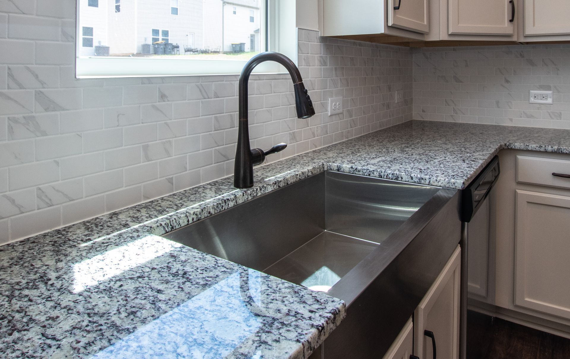 A kitchen with granite counter tops and a stainless steel sink.