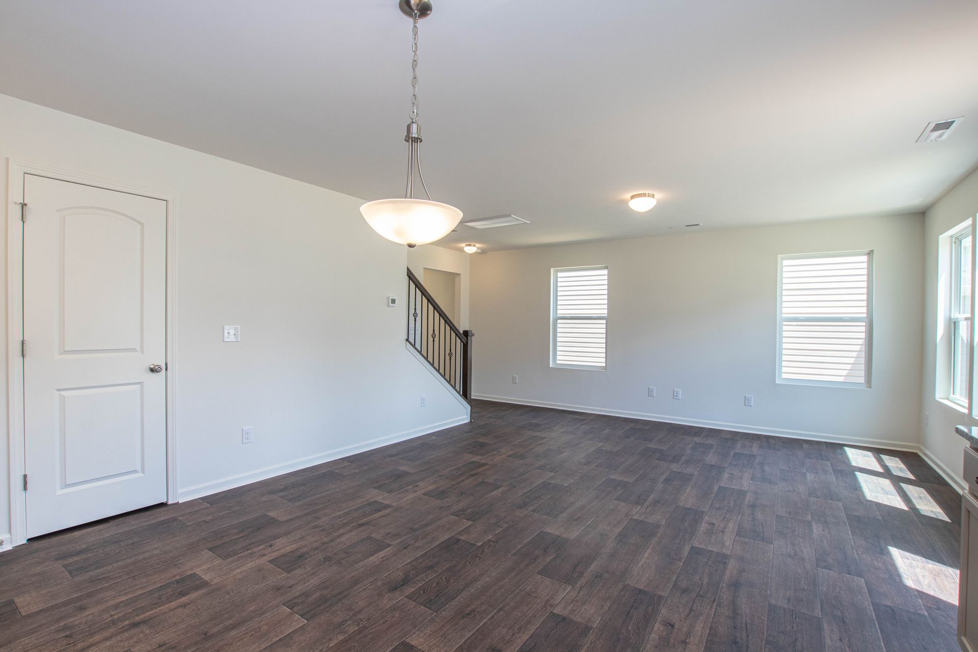 An empty living room with hardwood floors and a staircase.
