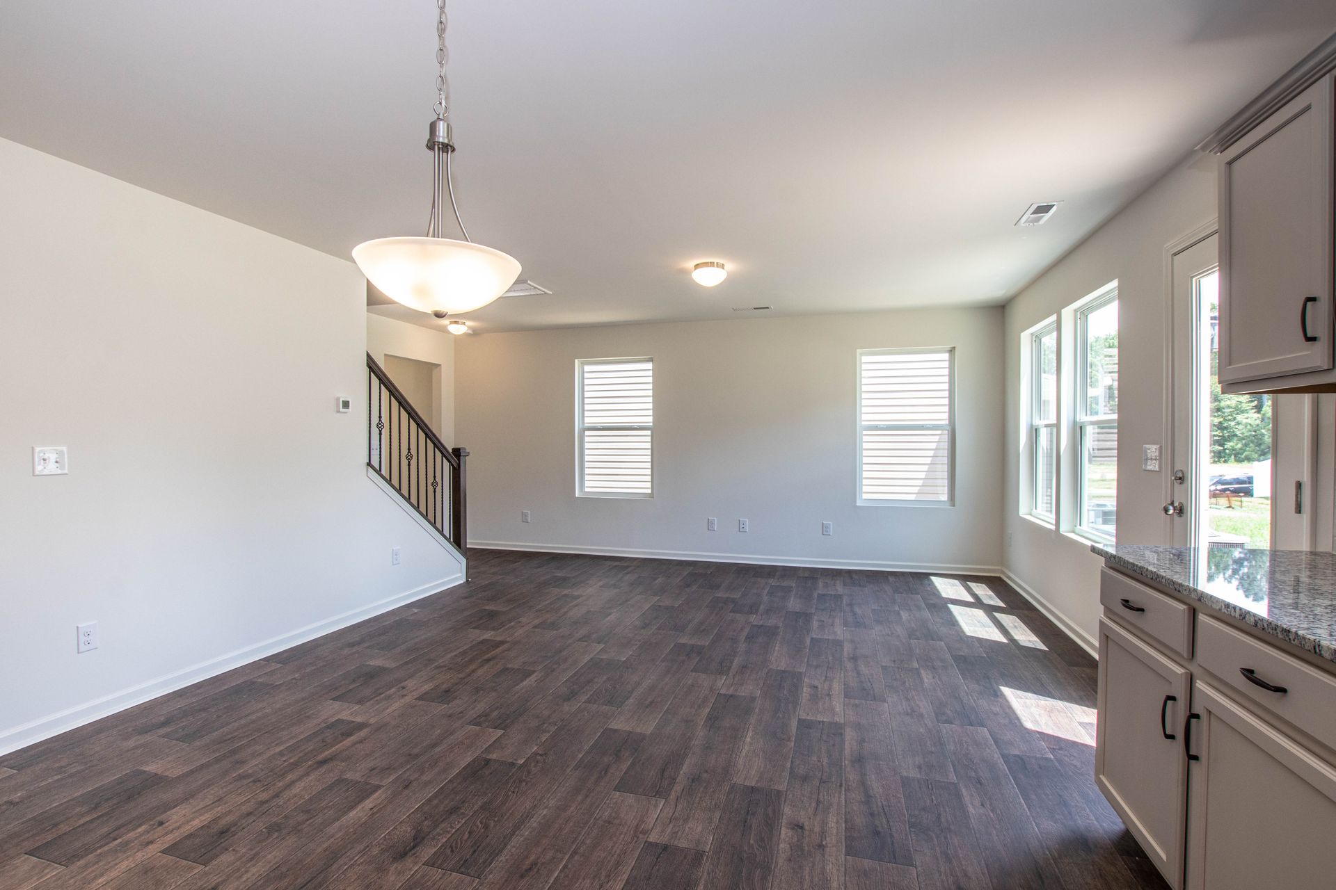 An empty living room with hardwood floors and a staircase in a house.