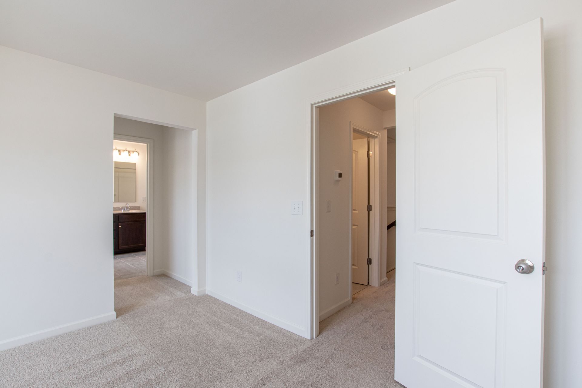 An empty bedroom with a carpeted floor and white walls.
