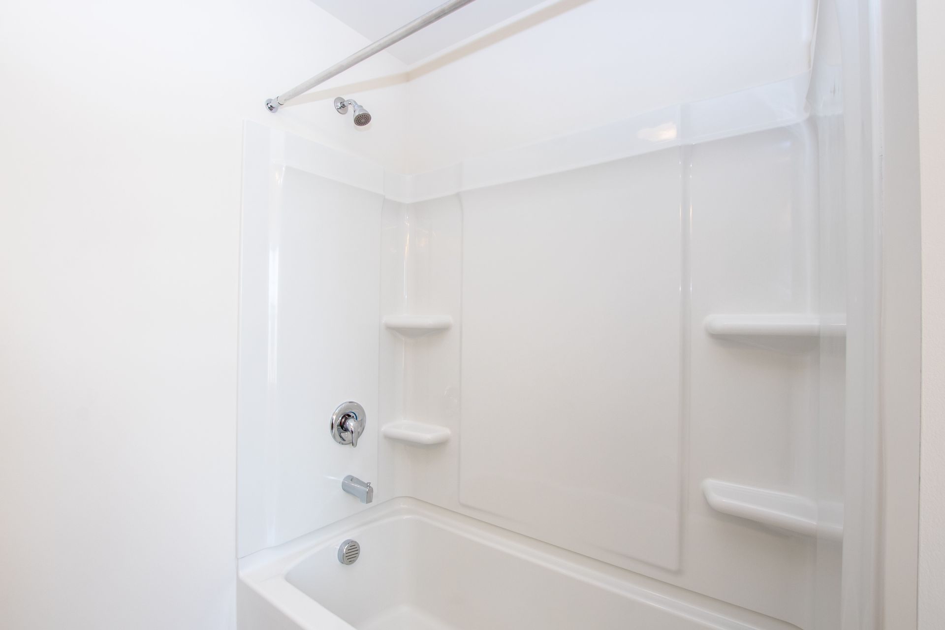 A bathroom with a bathtub , shower , and shelves.
