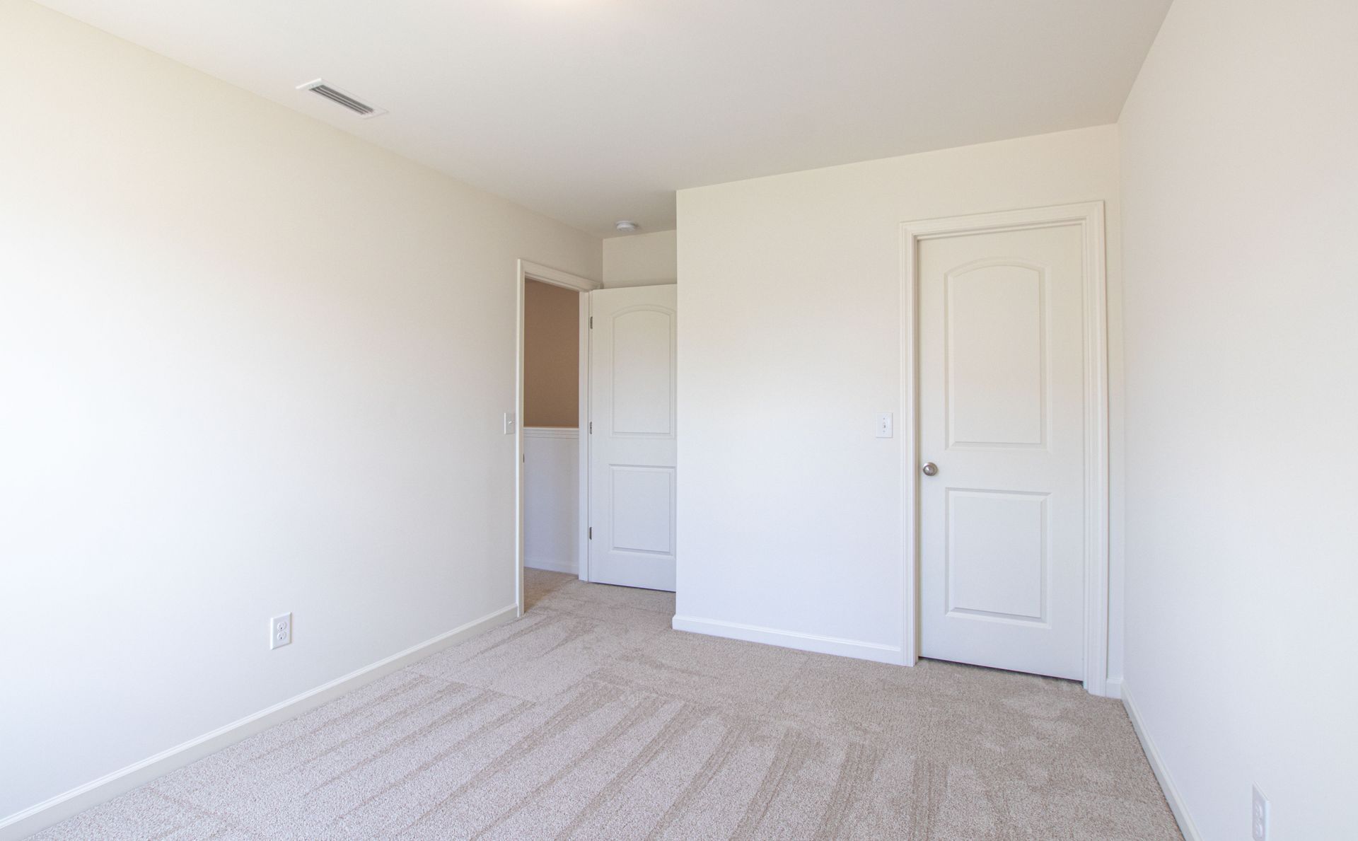 An empty bedroom with a carpeted floor and white walls.