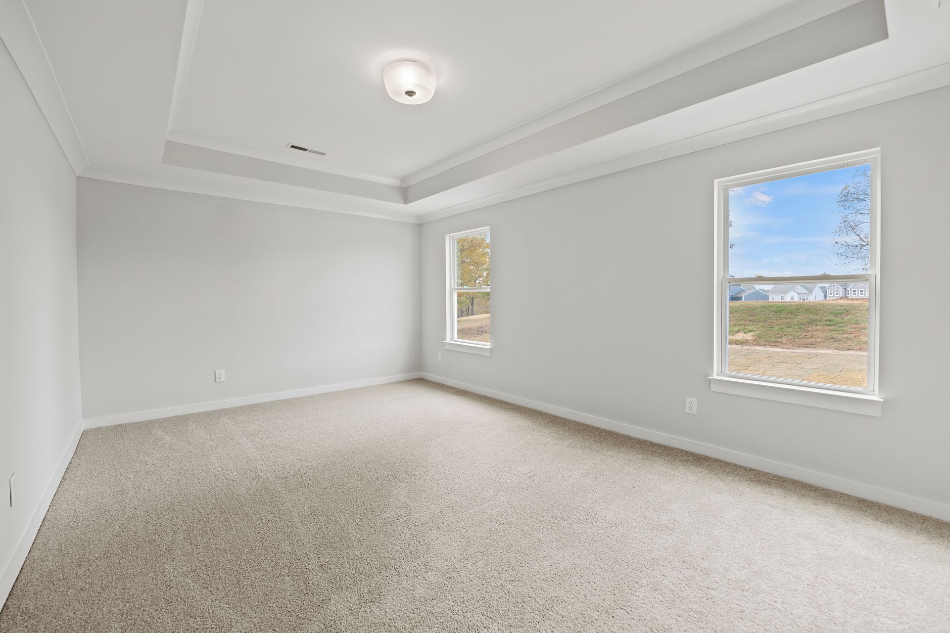 An empty bedroom with a ceiling fan and two windows.