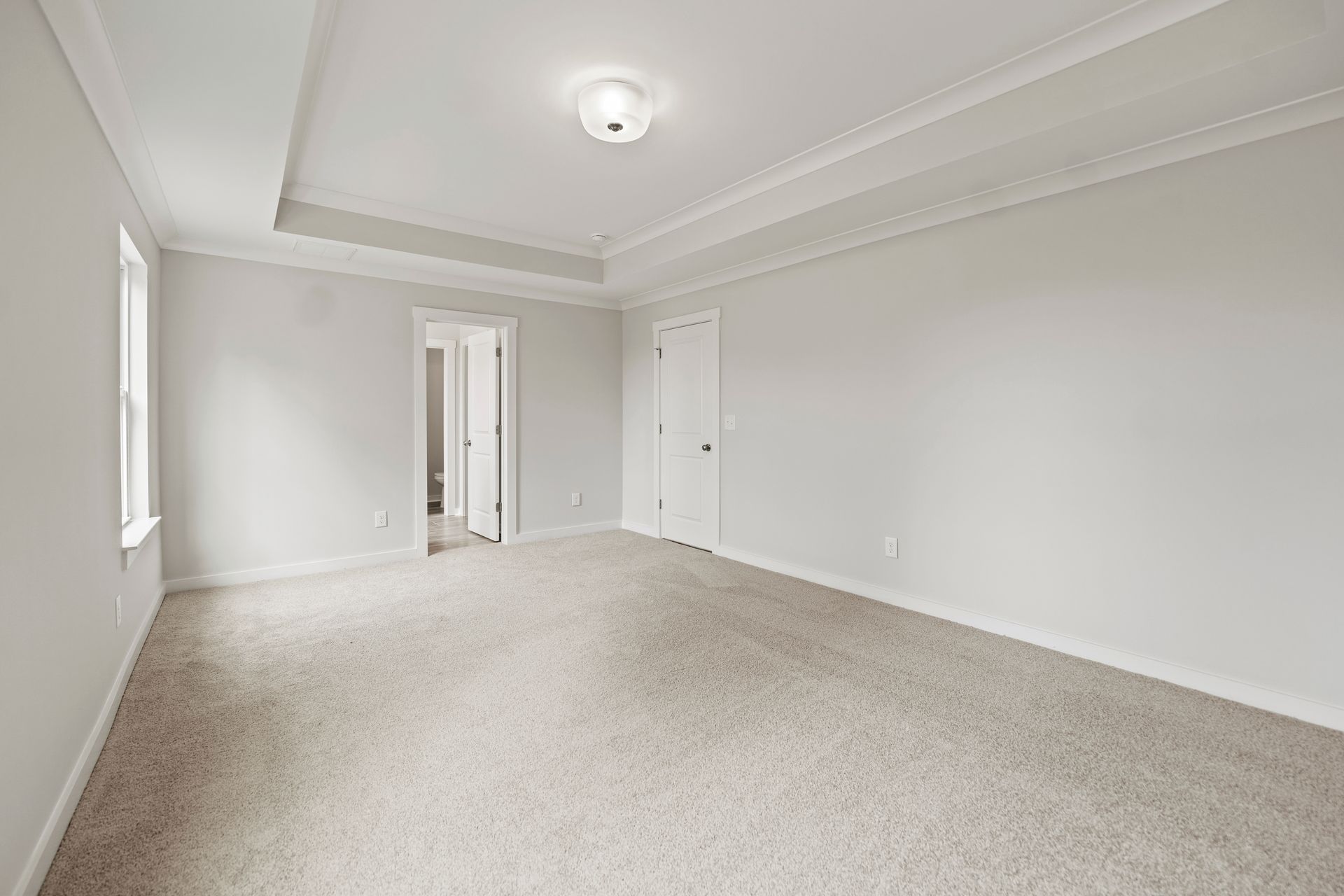 An empty bedroom with white walls and carpet.