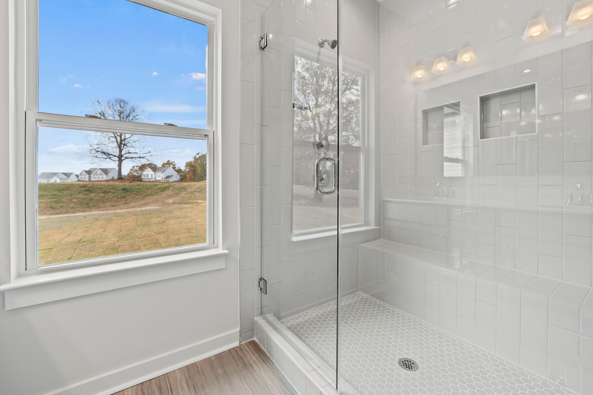 A bathroom with a walk in shower and a window.