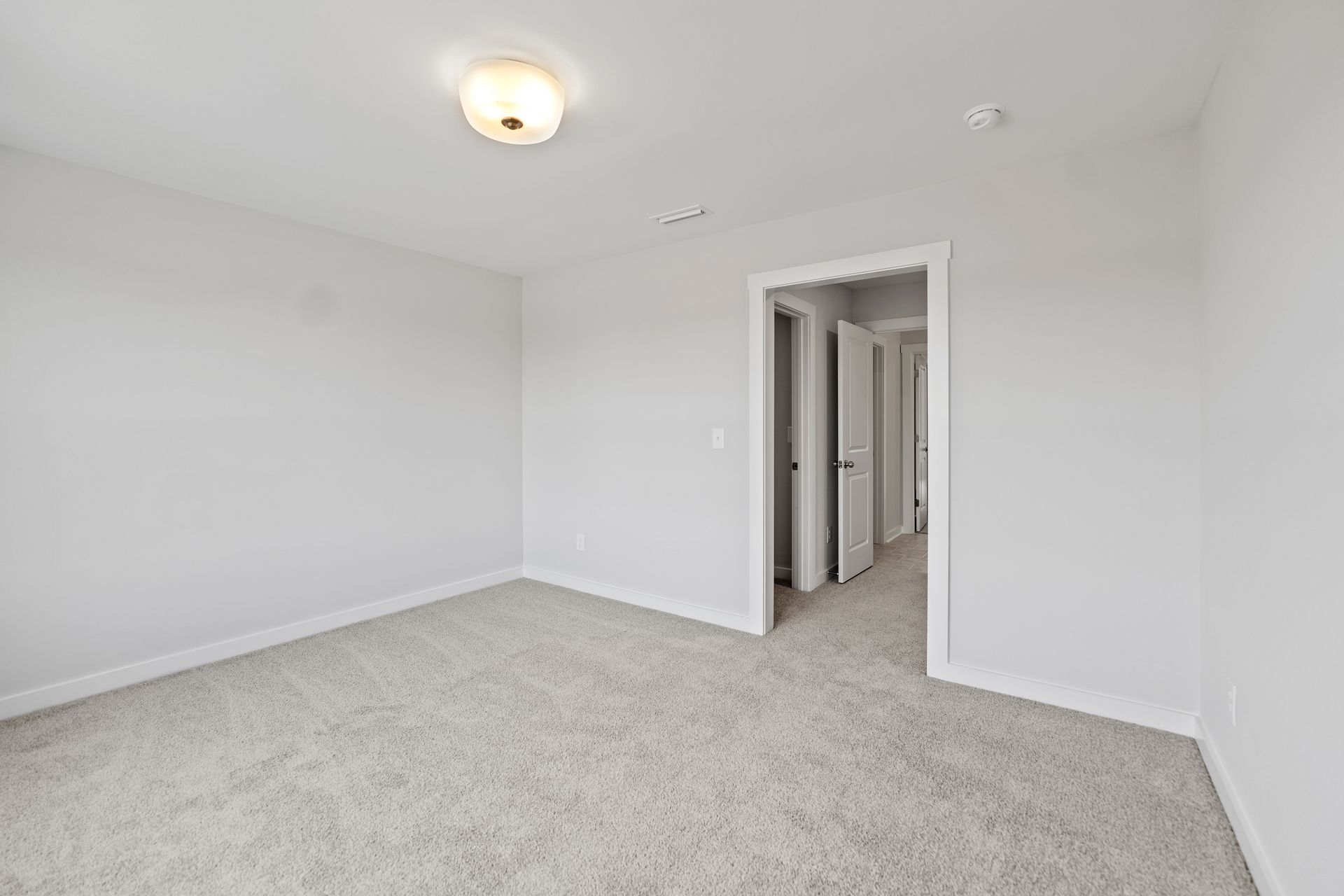 An empty bedroom with a carpeted floor and white walls.