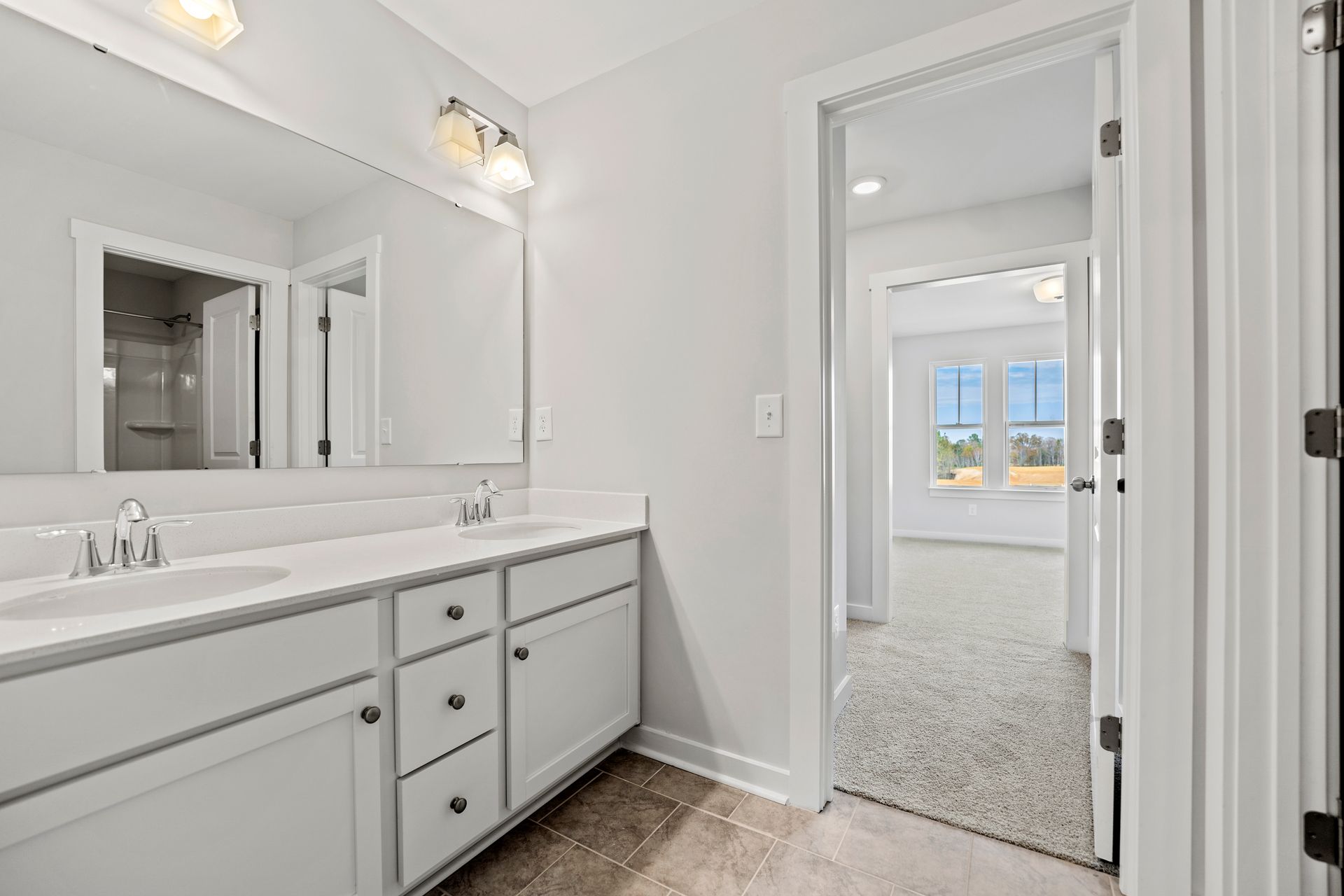 A bathroom with two sinks , a mirror and a walk in shower.