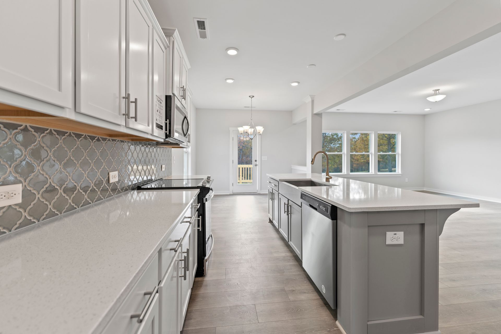 A kitchen with white cabinets , stainless steel appliances , and a large island.