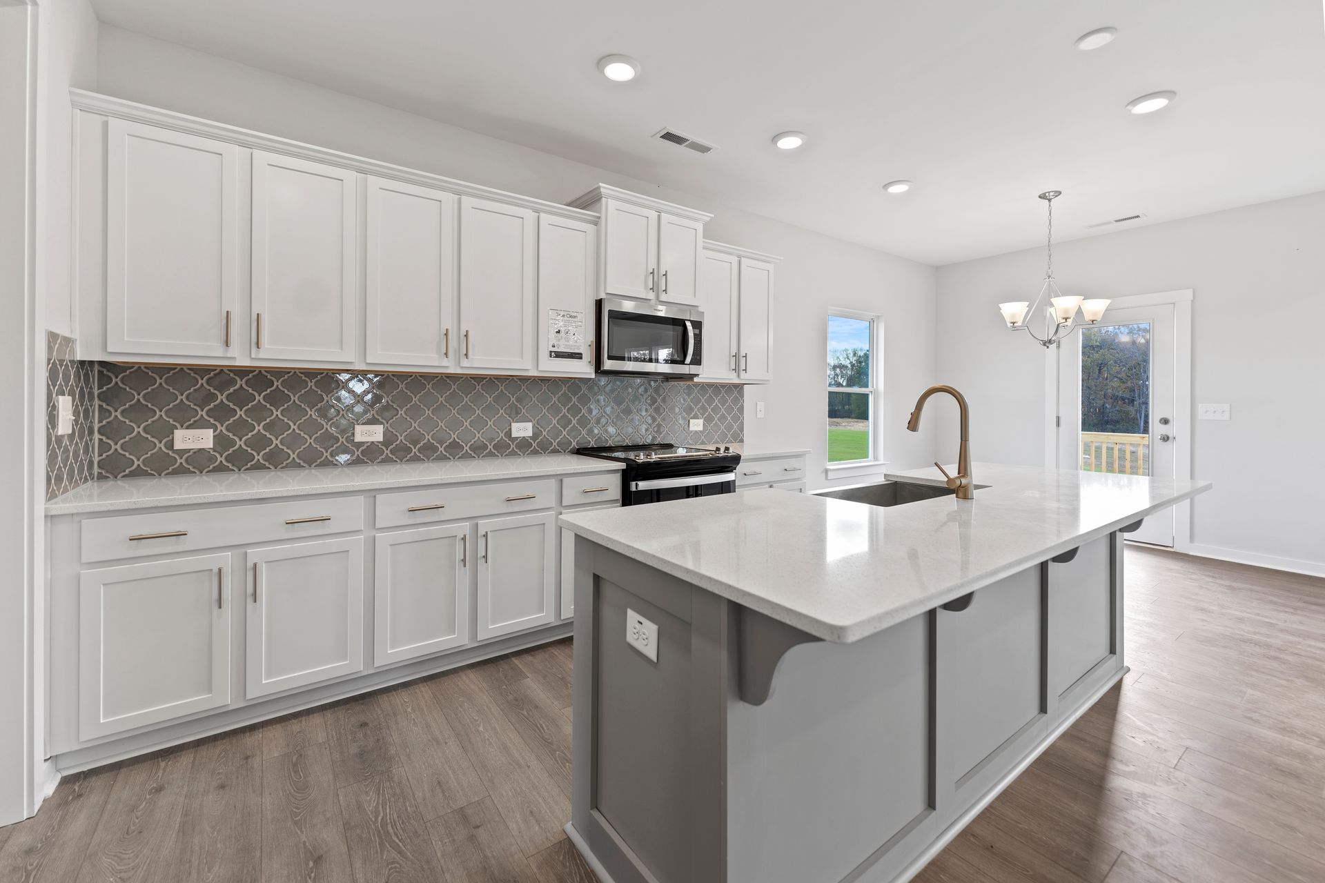 A kitchen in a new home with white cabinets and a large island.