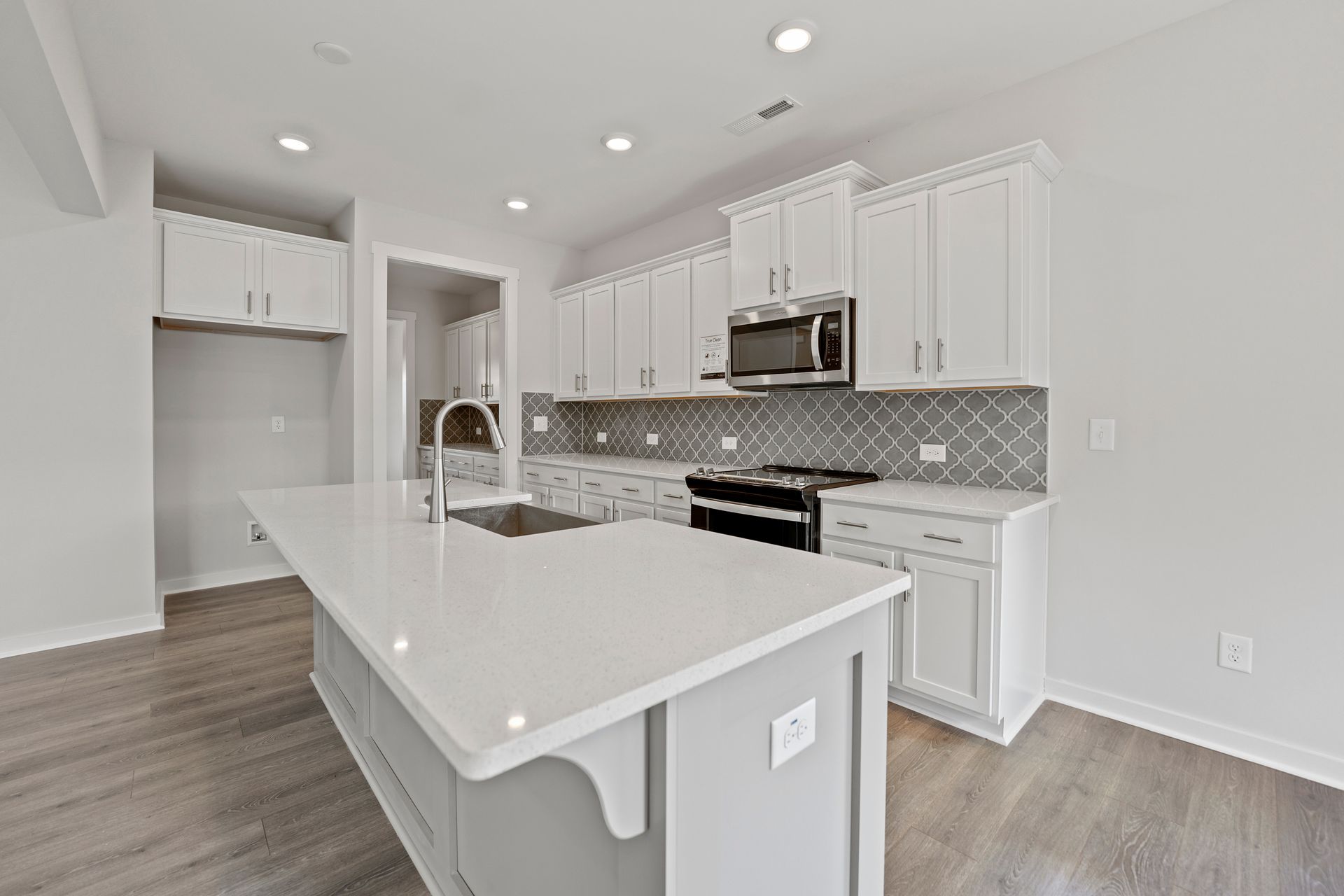 A kitchen with white cabinets , stainless steel appliances , and a large island.