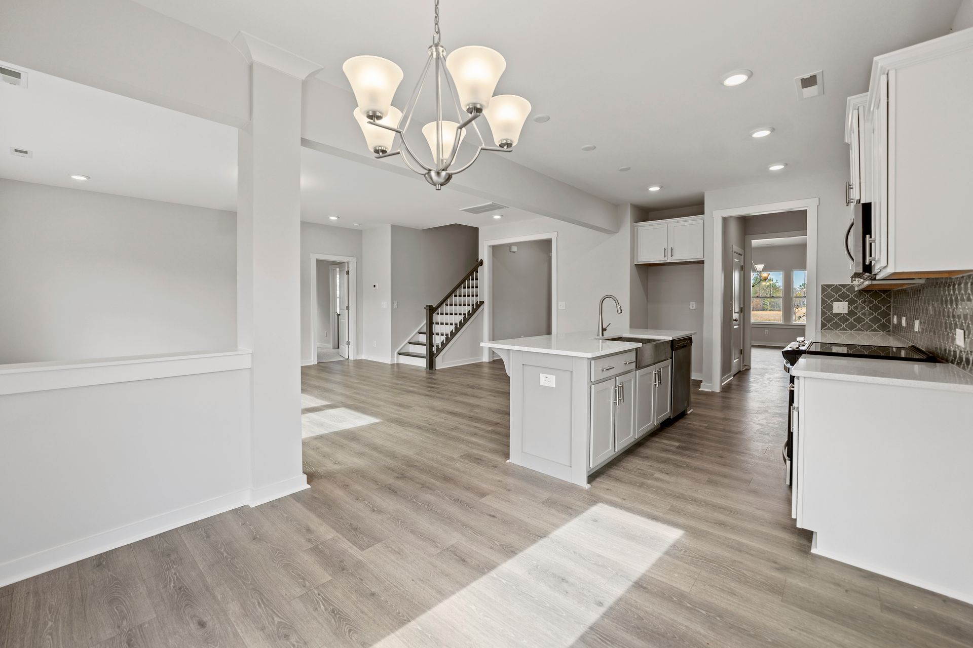A kitchen and dining room in a new home with hardwood floors and white cabinets.
