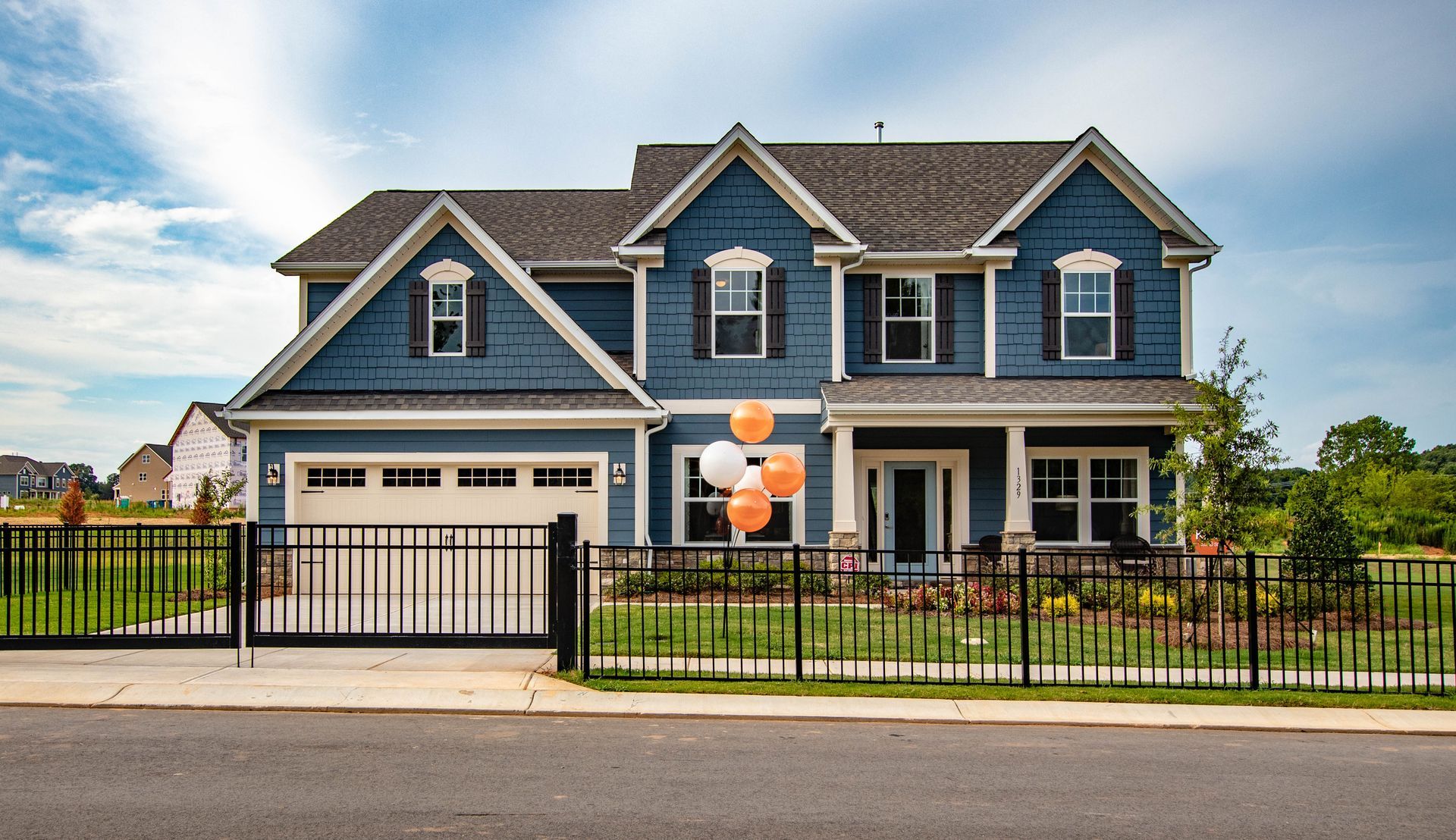 A blue house with orange balloons in front of it