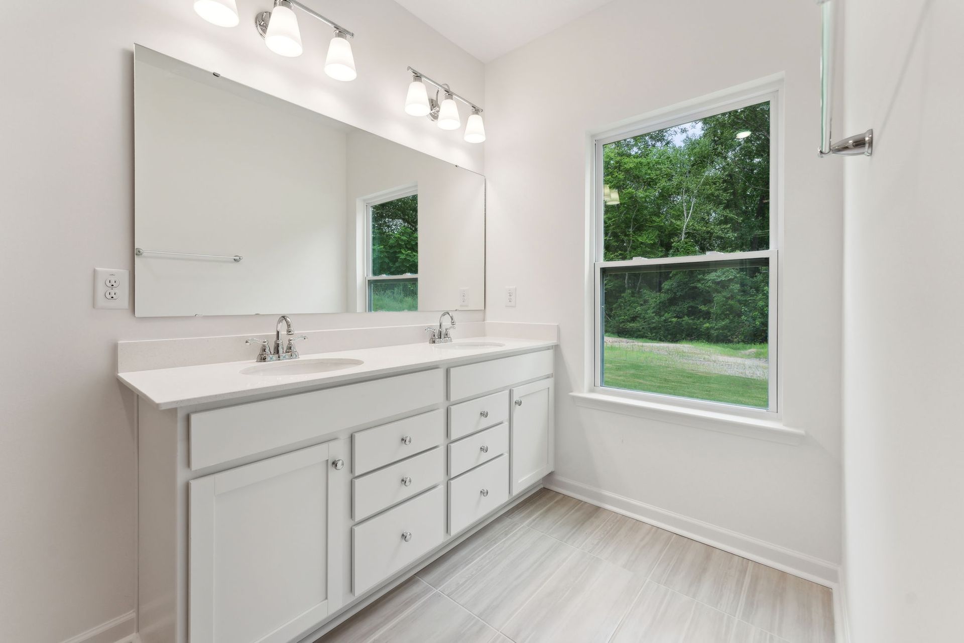 A bathroom with two sinks , a large mirror and a window.