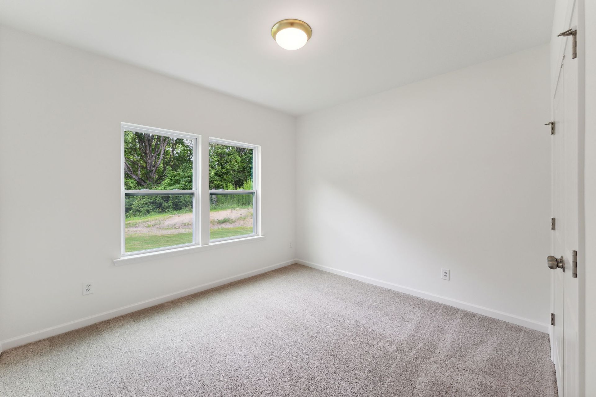 An empty bedroom with two windows and a ceiling light.