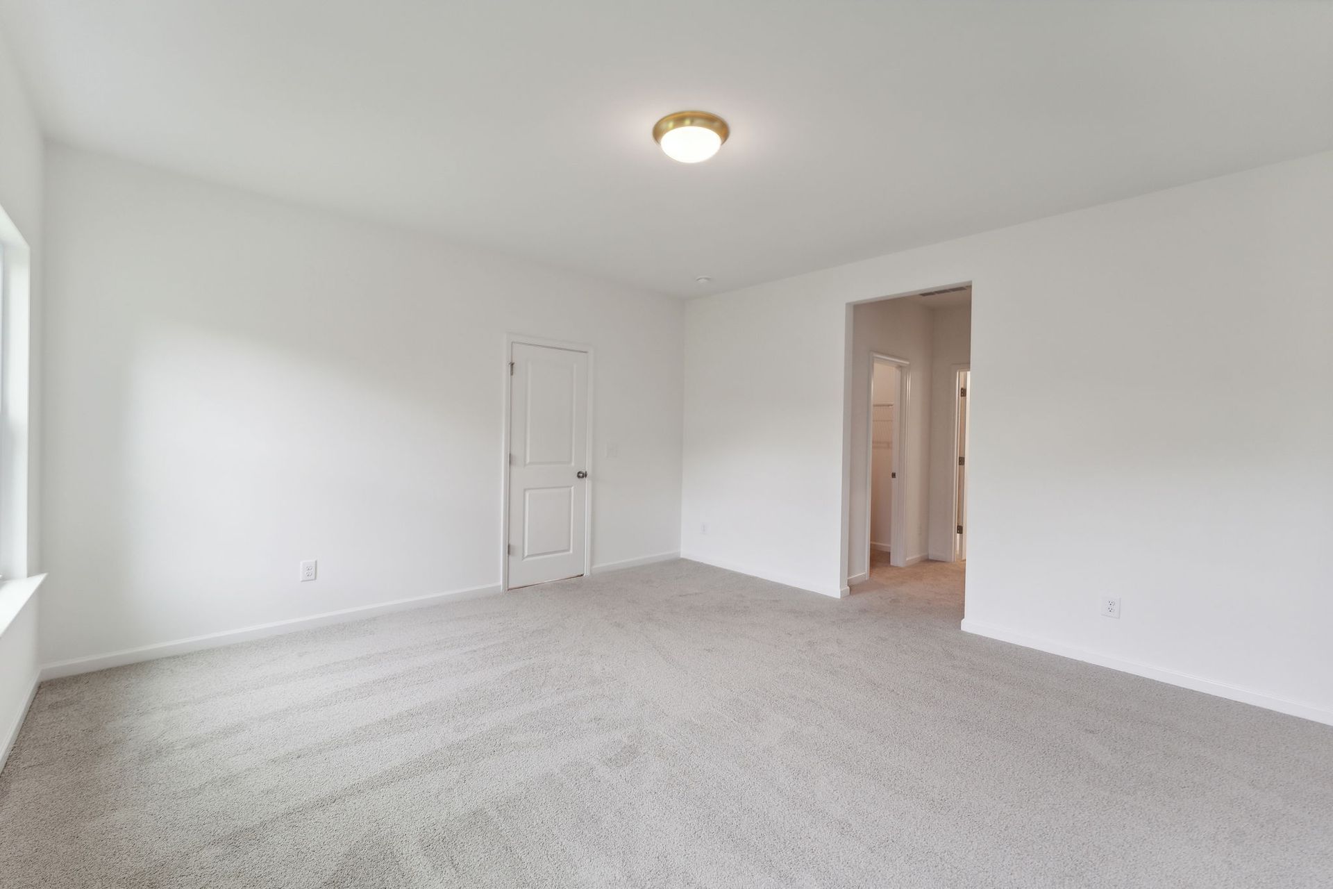 An empty living room with a carpeted floor and white walls.