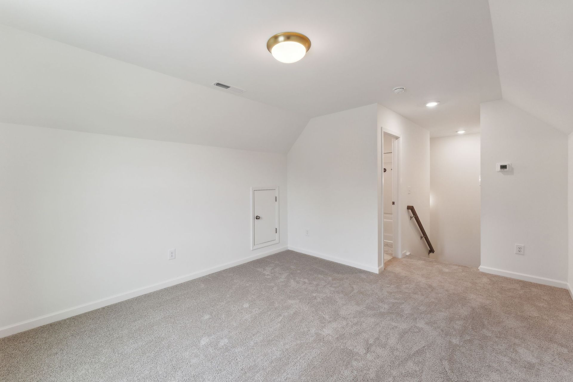 An empty room with a carpeted floor and white walls.