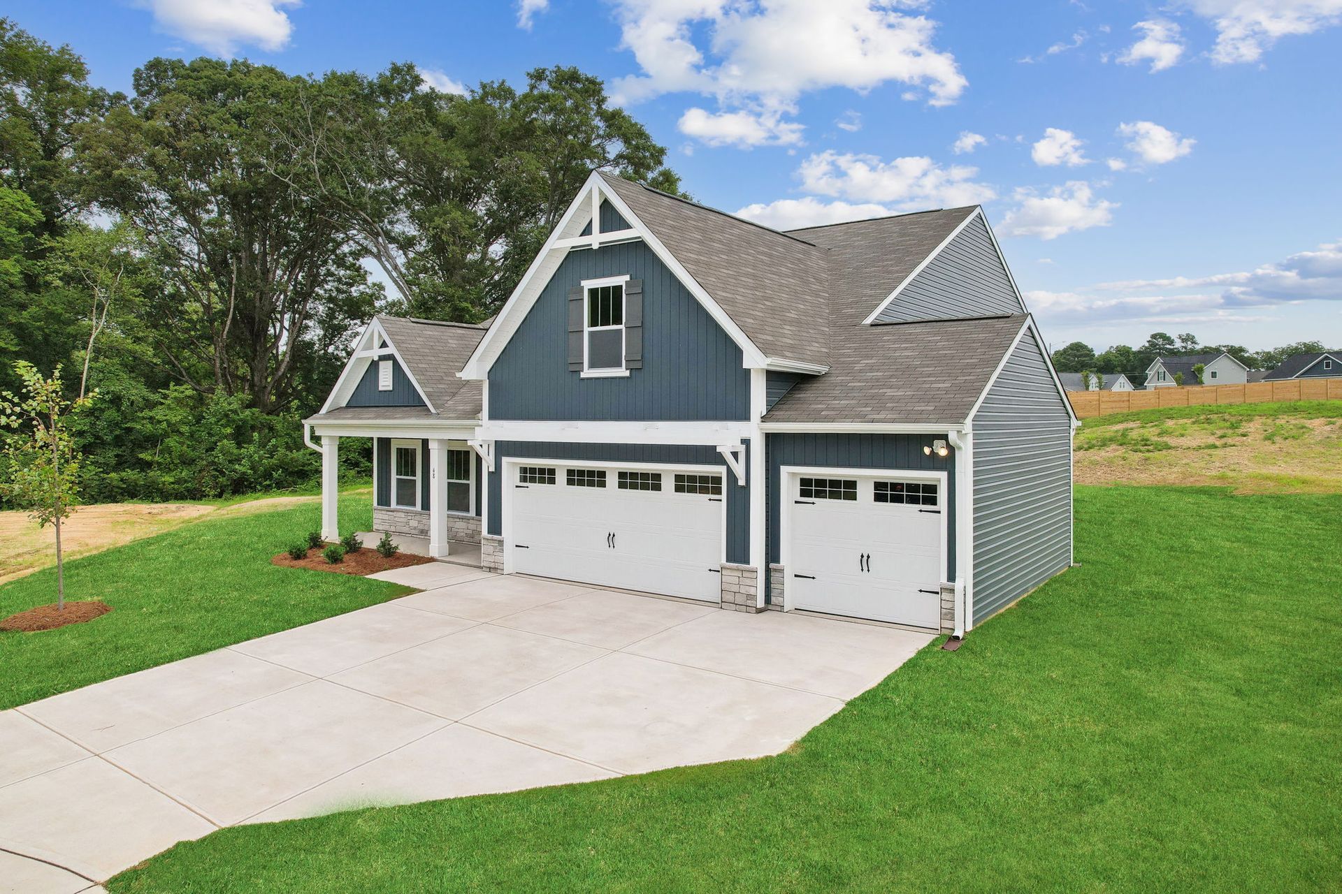 A blue and white house with two garages and a driveway.