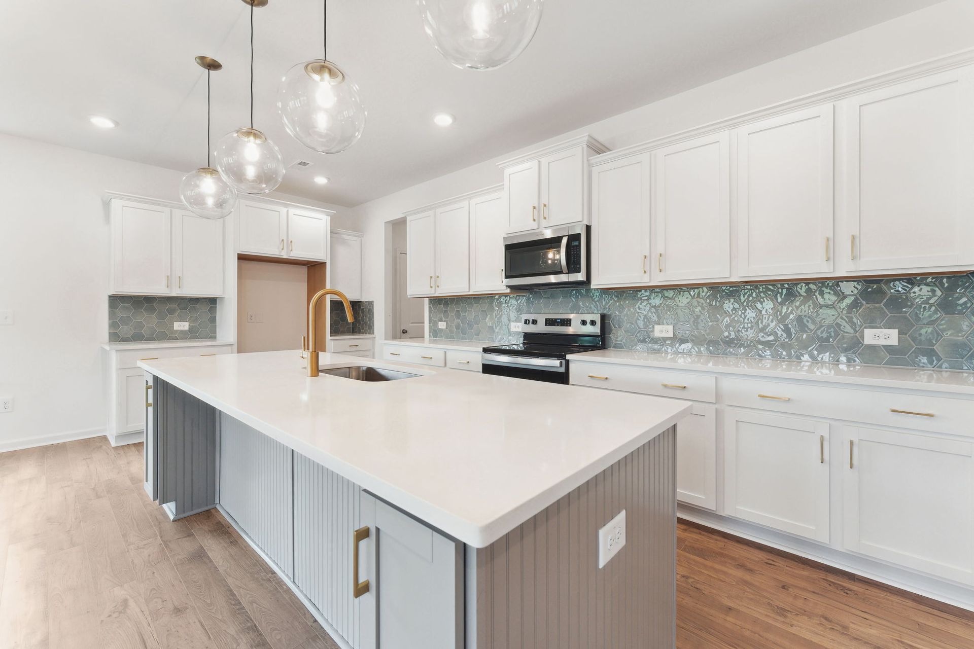 A kitchen with white cabinets and a large island in the middle.
