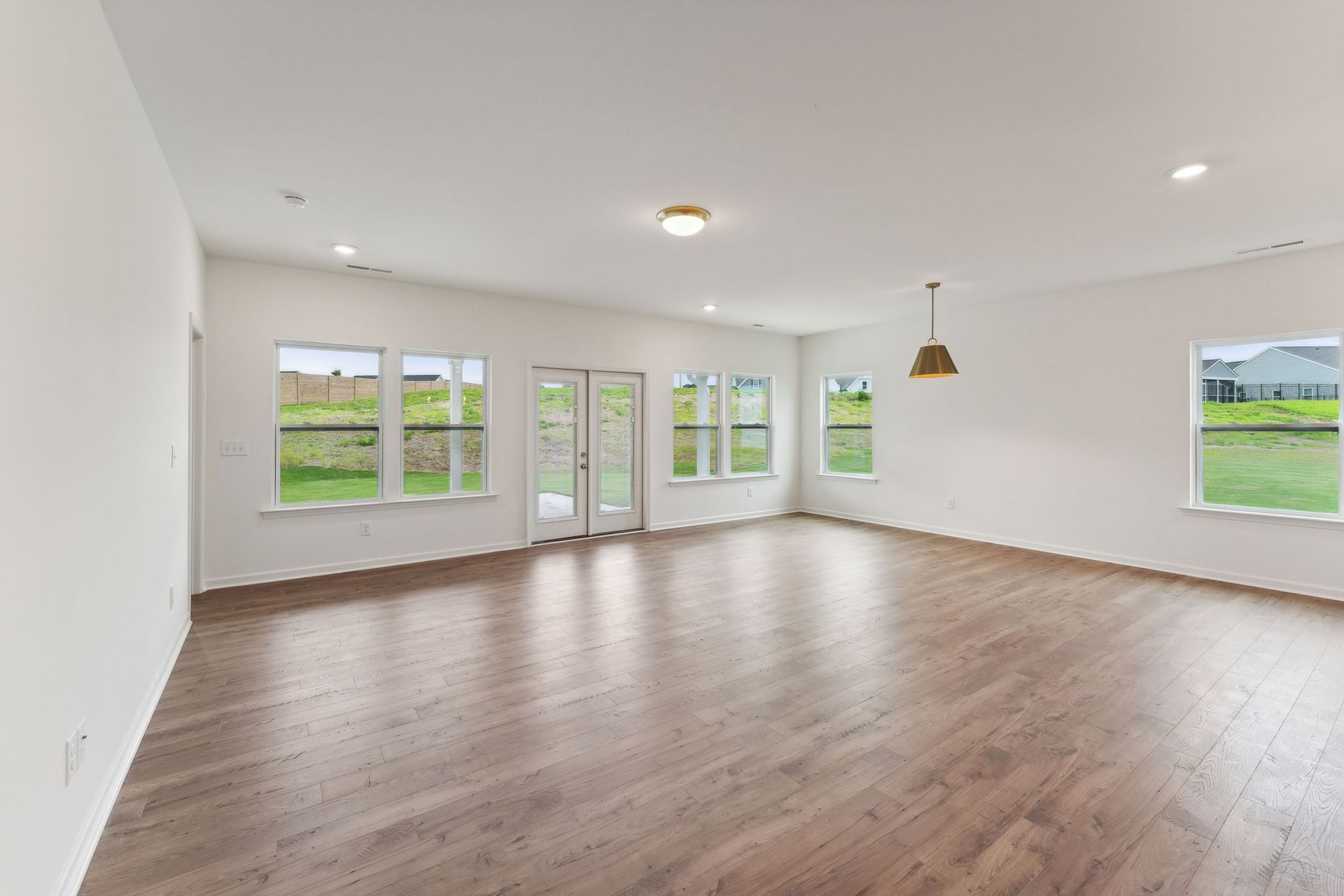 An empty living room with hardwood floors and white walls.
