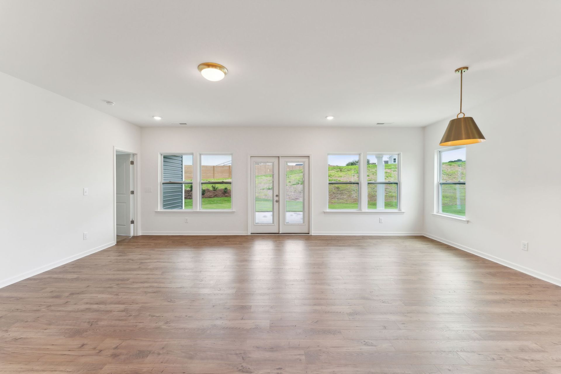 An empty living room with hardwood floors and white walls.