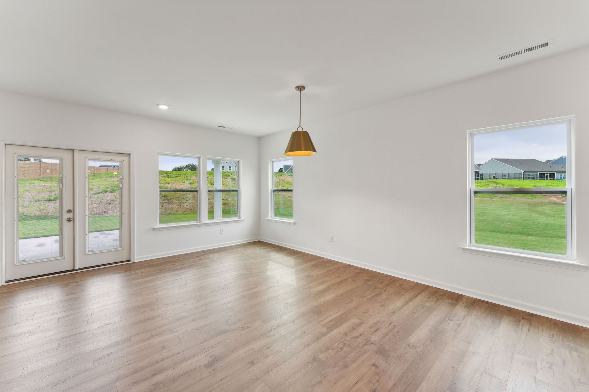 An empty living room with hardwood floors and white walls.