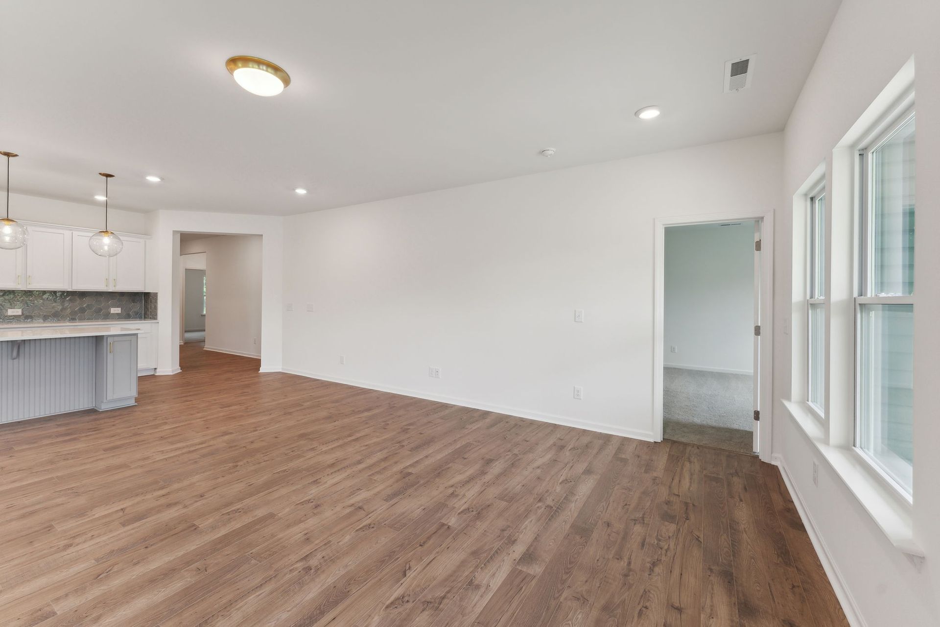 An empty living room with hardwood floors and white walls.