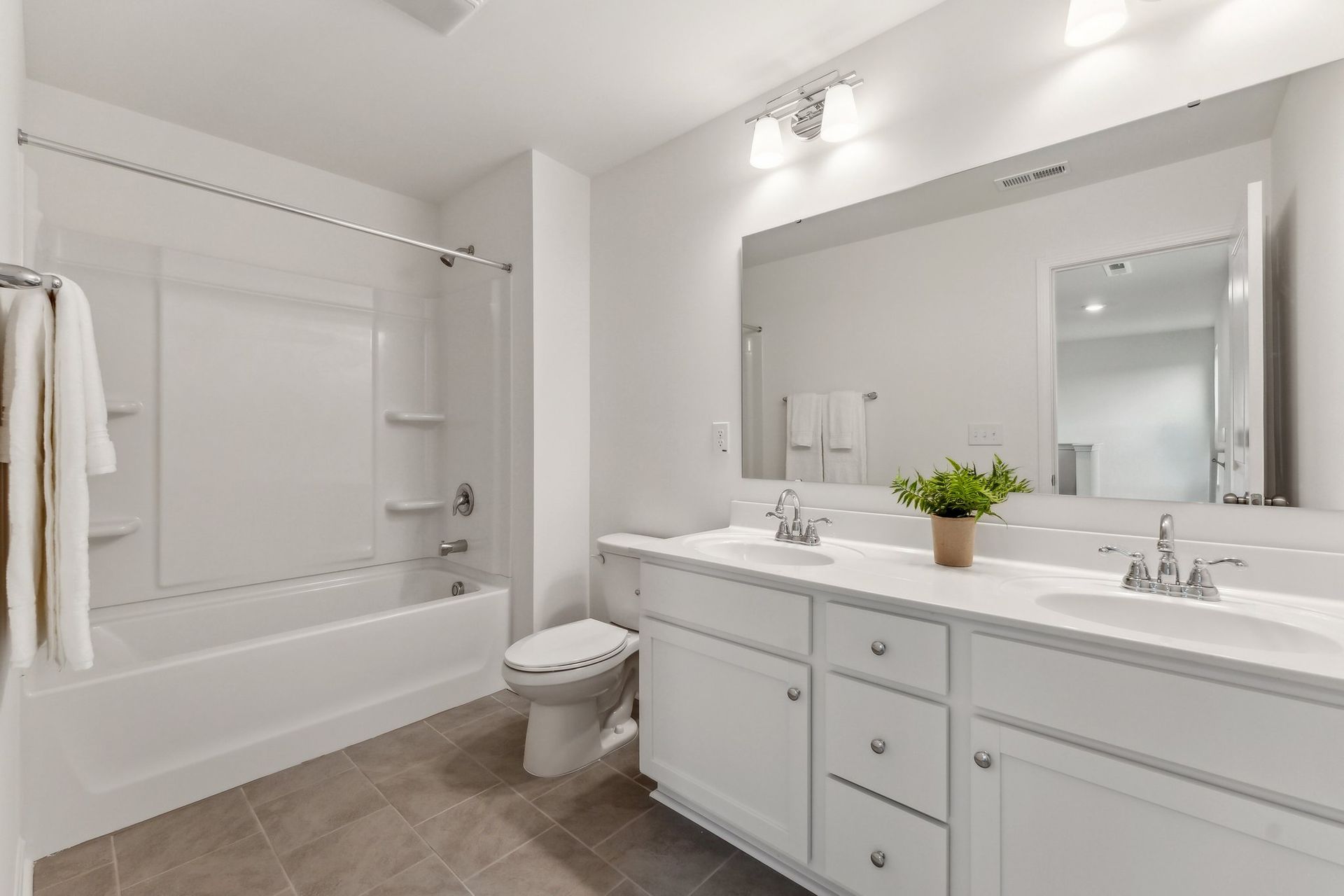 A bathroom with a toilet , sink , tub and mirror.