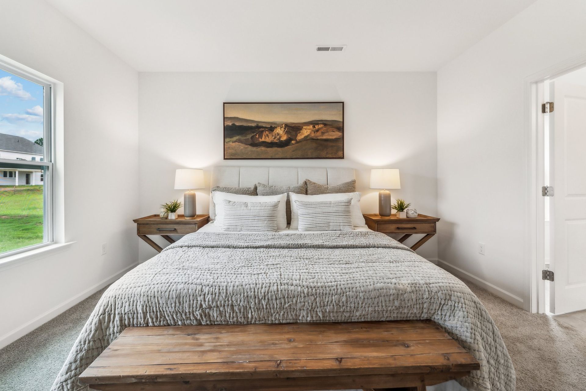 A bedroom with a bed , nightstands , lamps and a window.