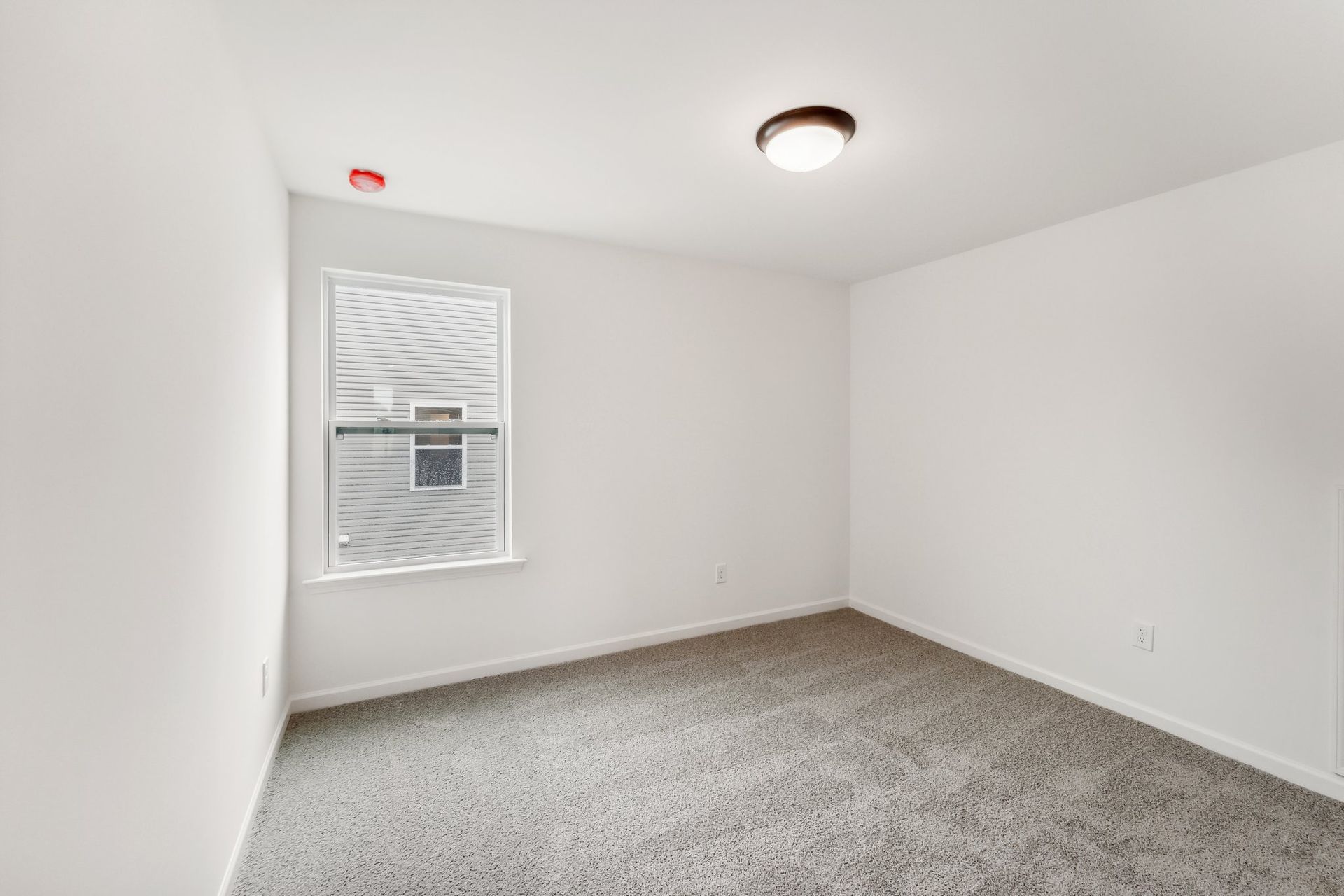 An empty bedroom with a window and a light on the ceiling.