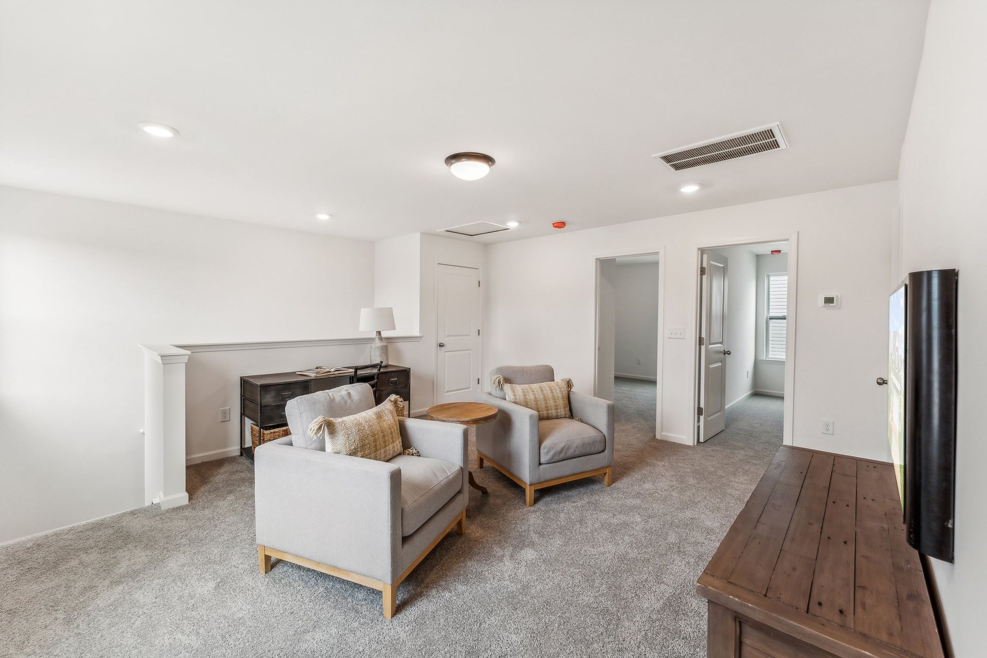 A living room with two chairs , a table and a television.