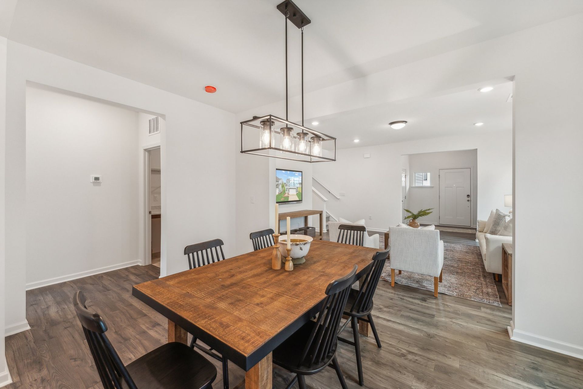 A dining room with a wooden table and chairs and a chandelier.