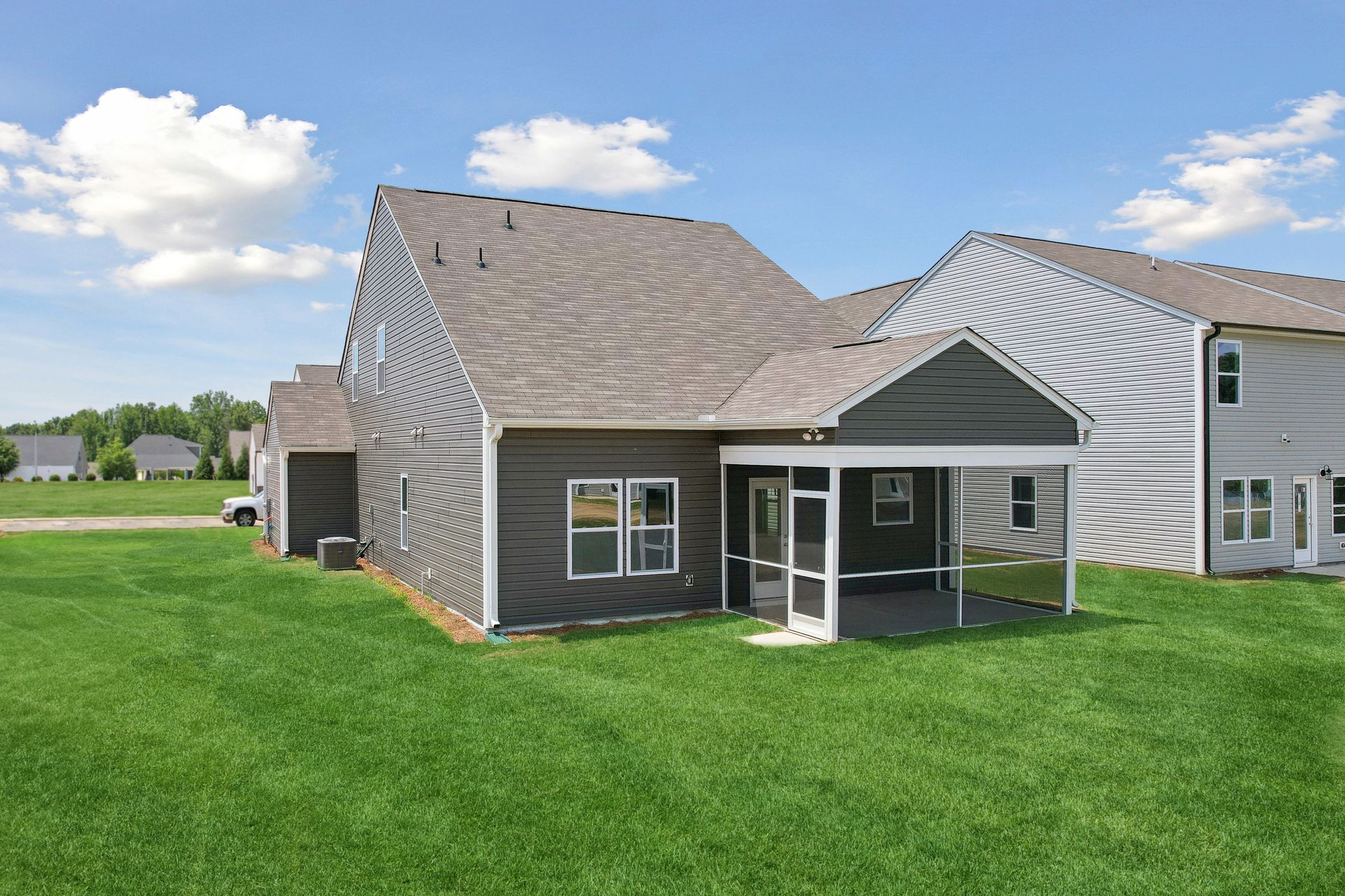 The back of a house with a screened in porch and a covered patio.