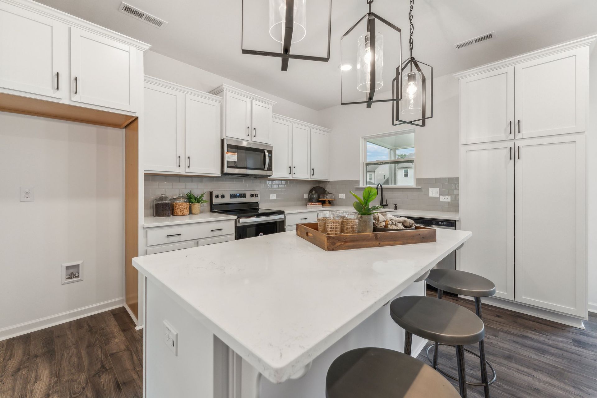 A kitchen with white cabinets , stainless steel appliances , and a large island.