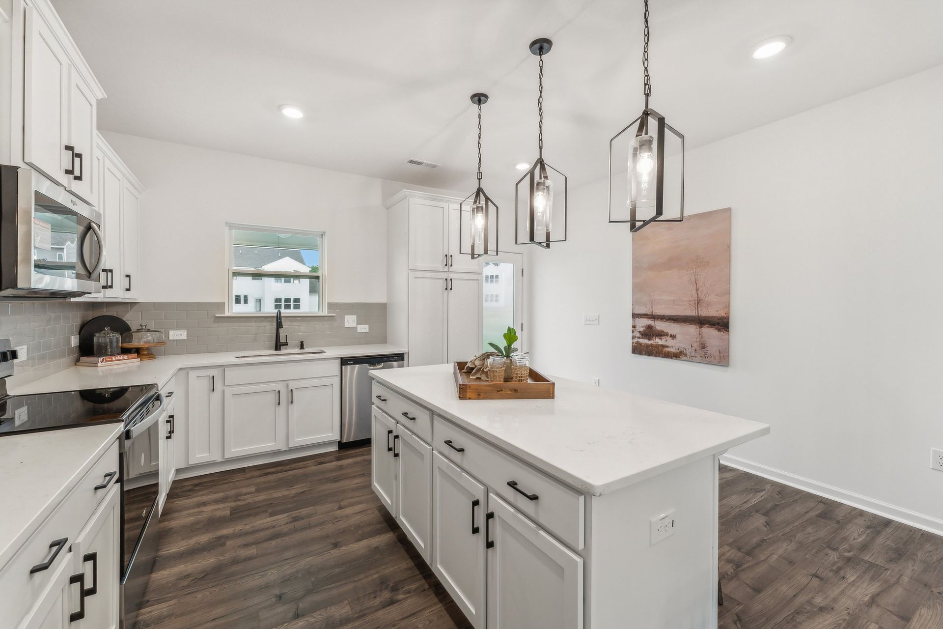 A kitchen with white cabinets , stainless steel appliances , and a large island.