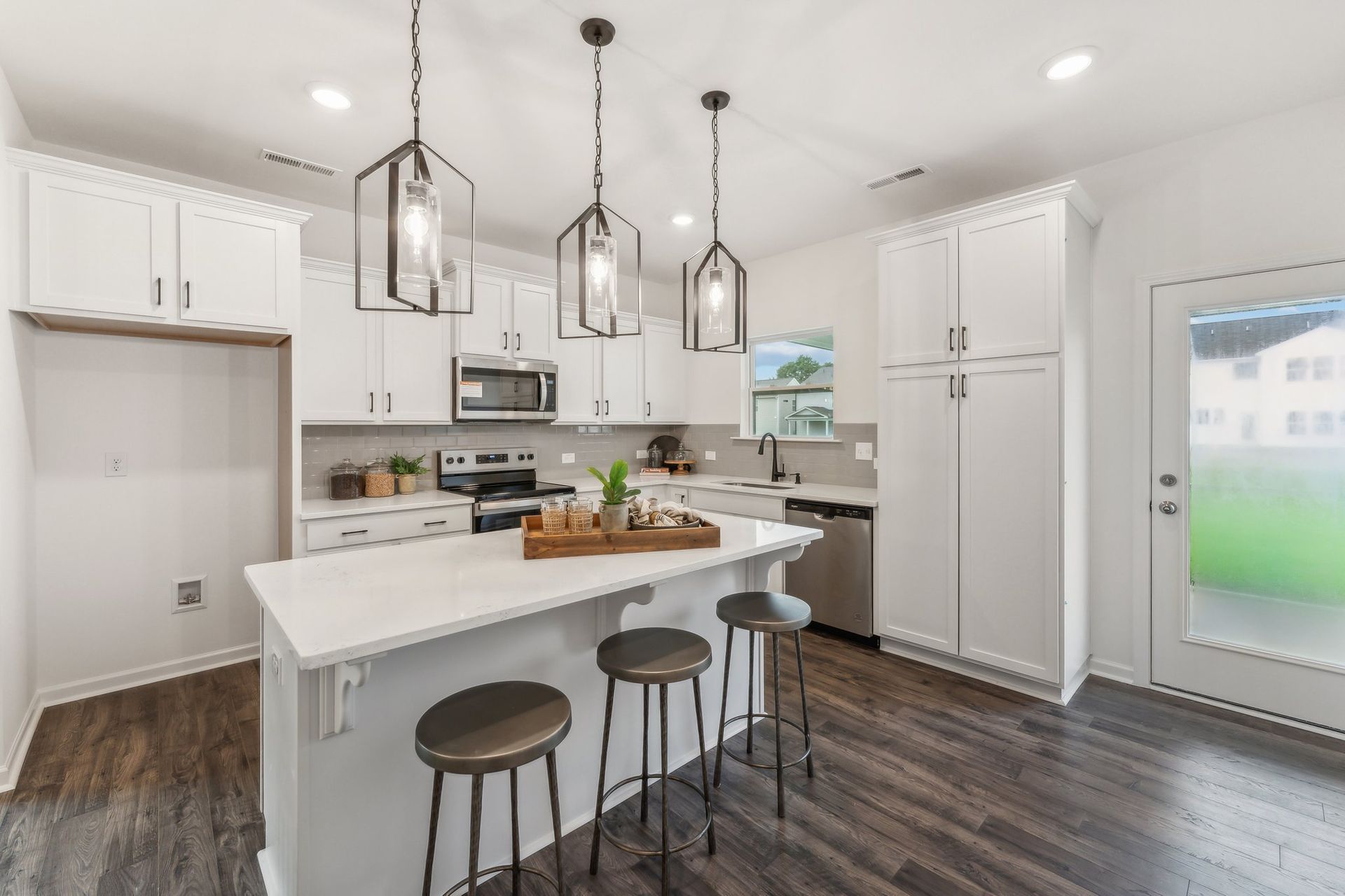 A kitchen with white cabinets , stainless steel appliances , and a large island.