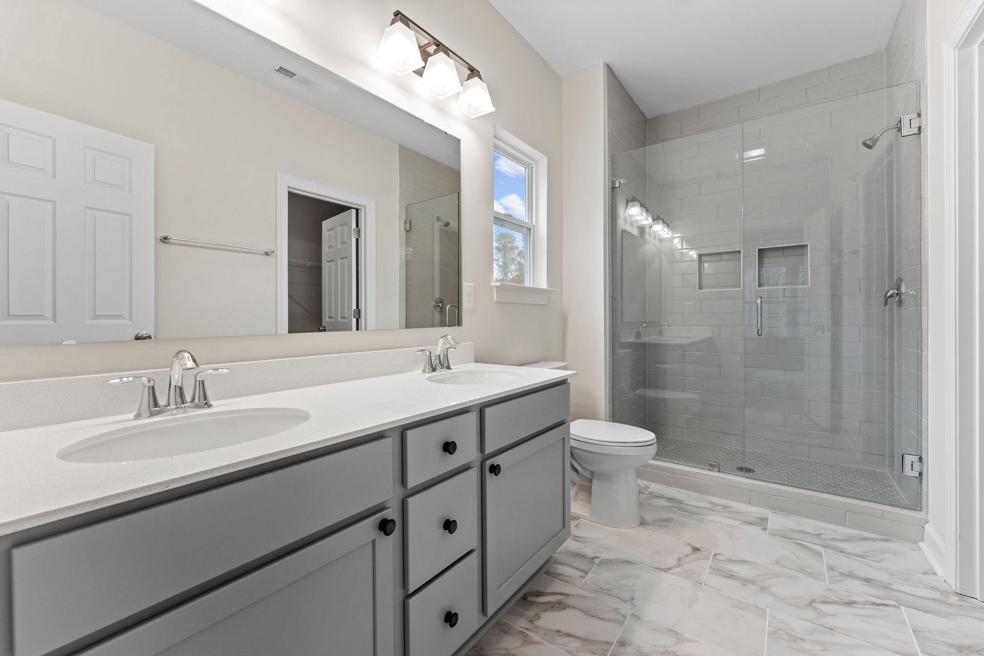 A bathroom with two sinks , a toilet , and a walk in shower.