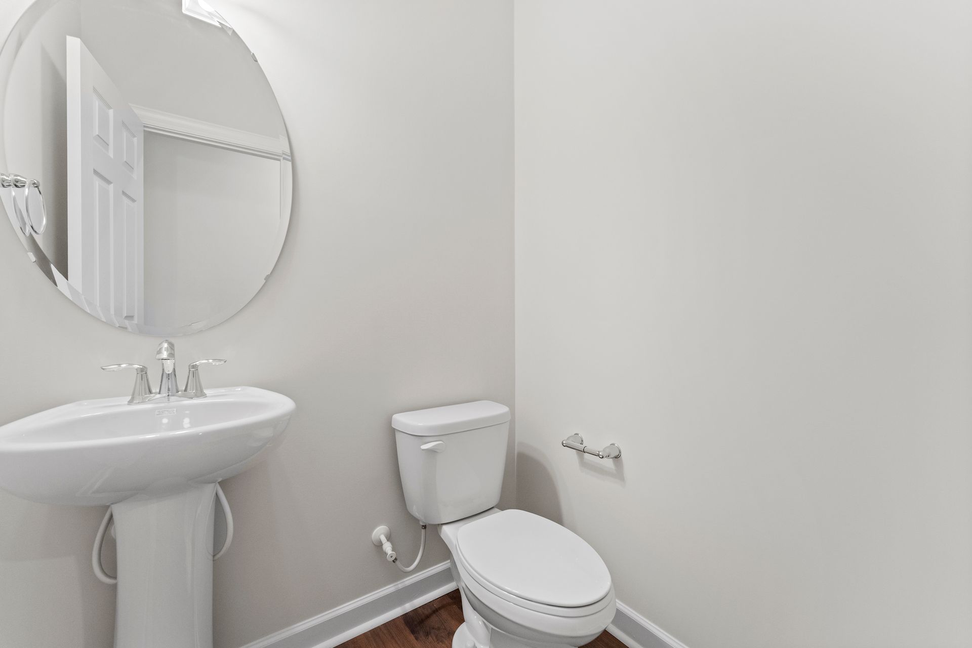 A bathroom with a toilet , sink and mirror.