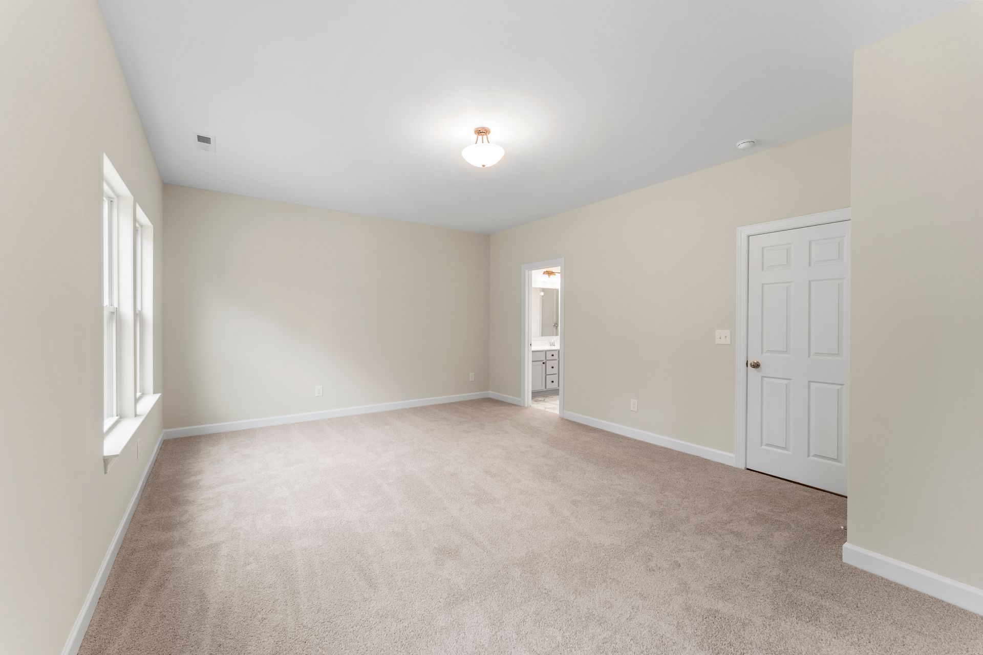 A large empty room with a carpeted floor and white walls.