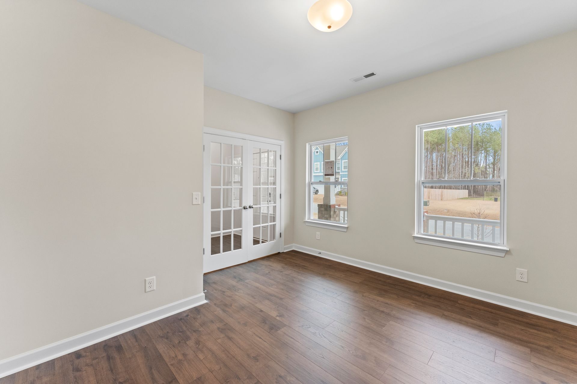 An empty living room with hardwood floors and french doors.