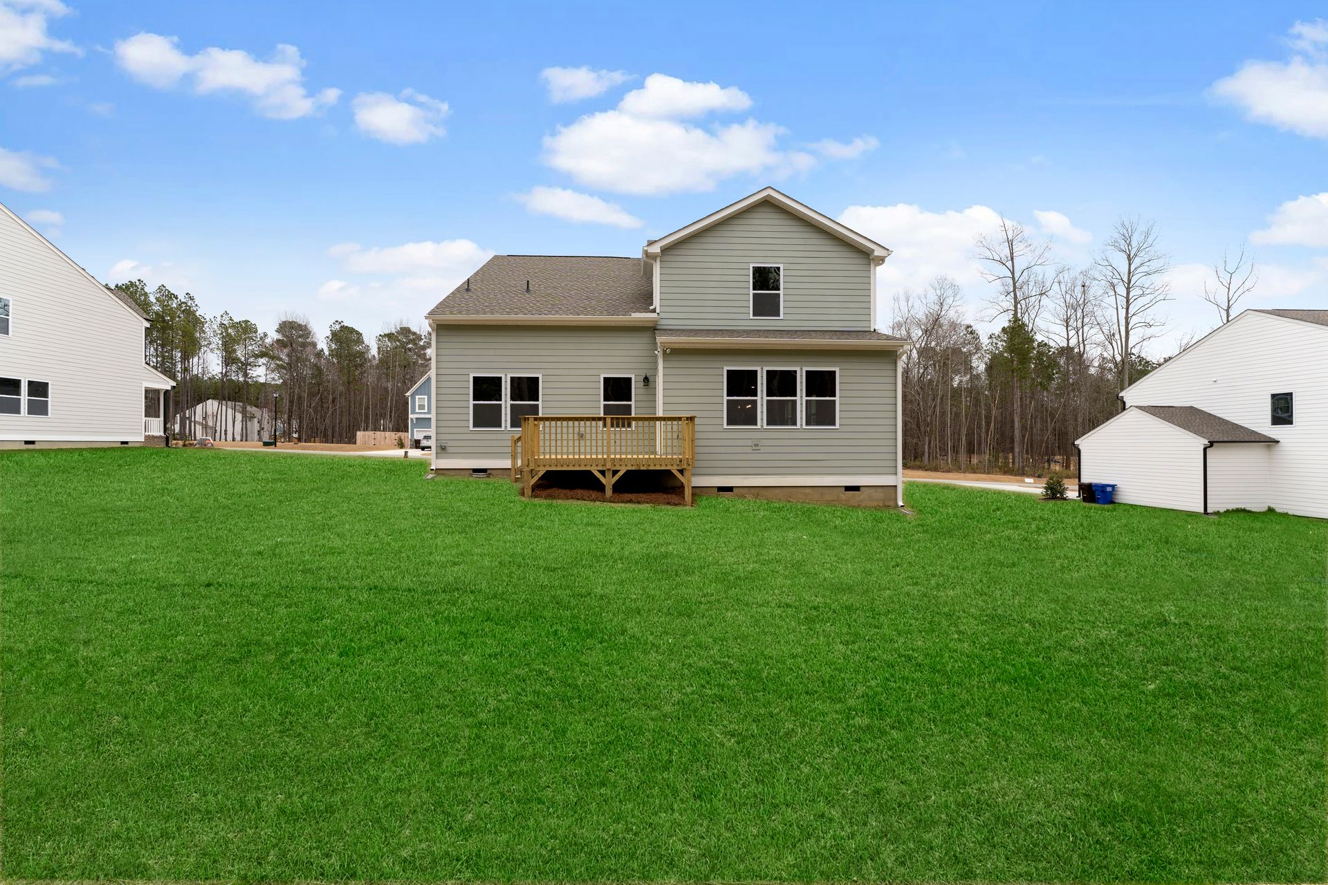 The back of a house with a large lawn in front of it.