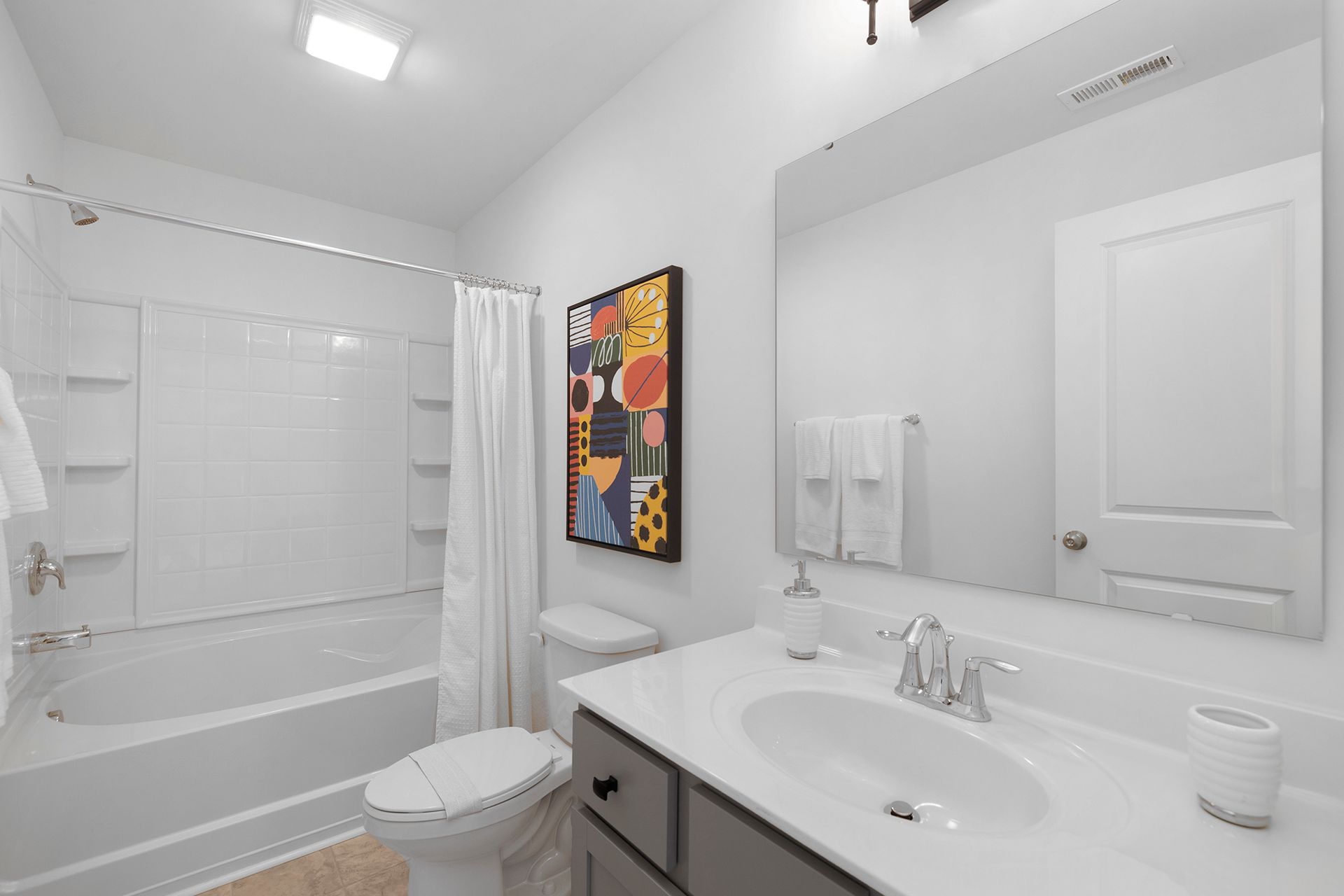 A bathroom with a toilet , sink , bathtub and mirror.