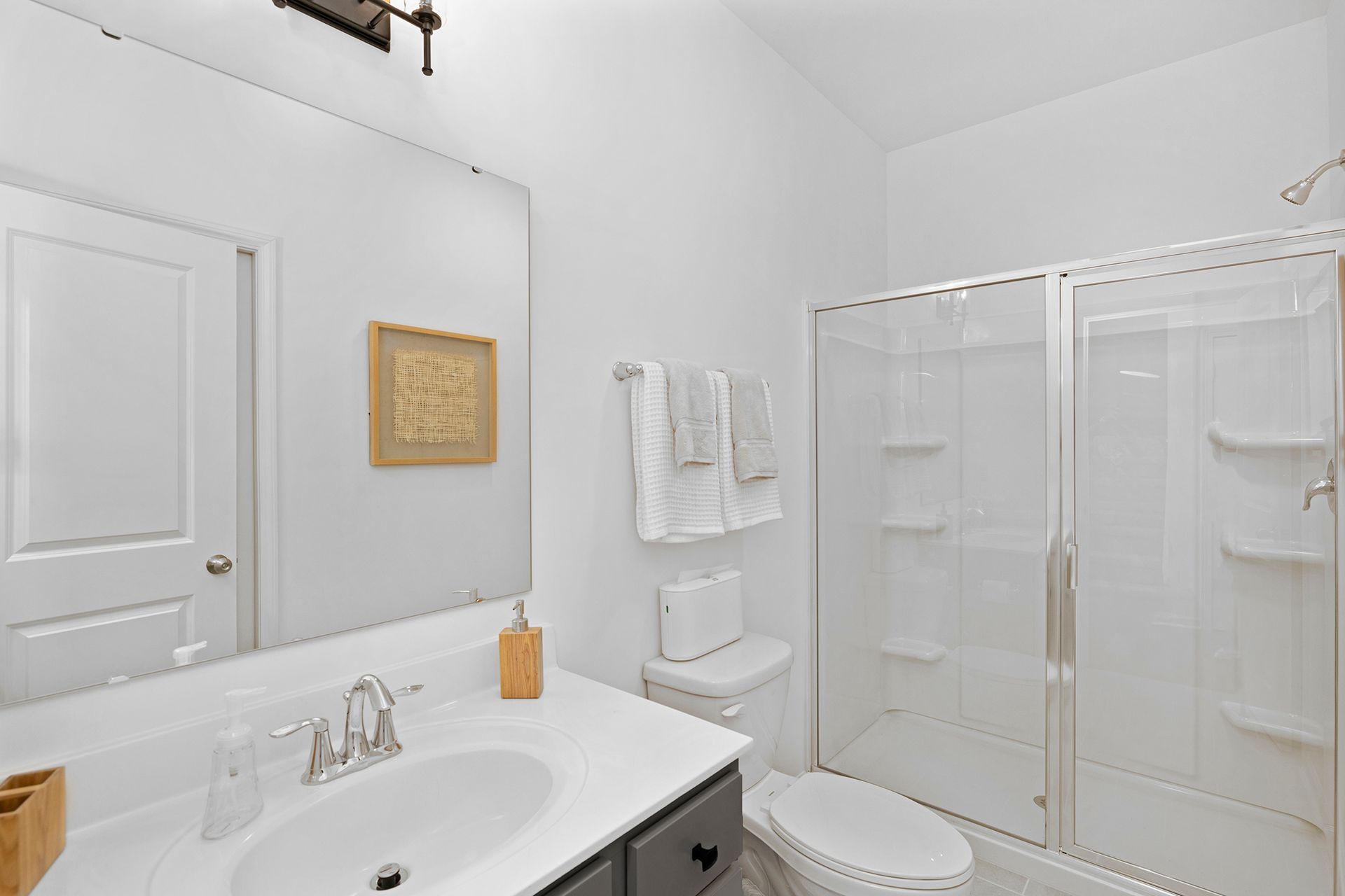 A bathroom with a sink , toilet , shower and mirror.