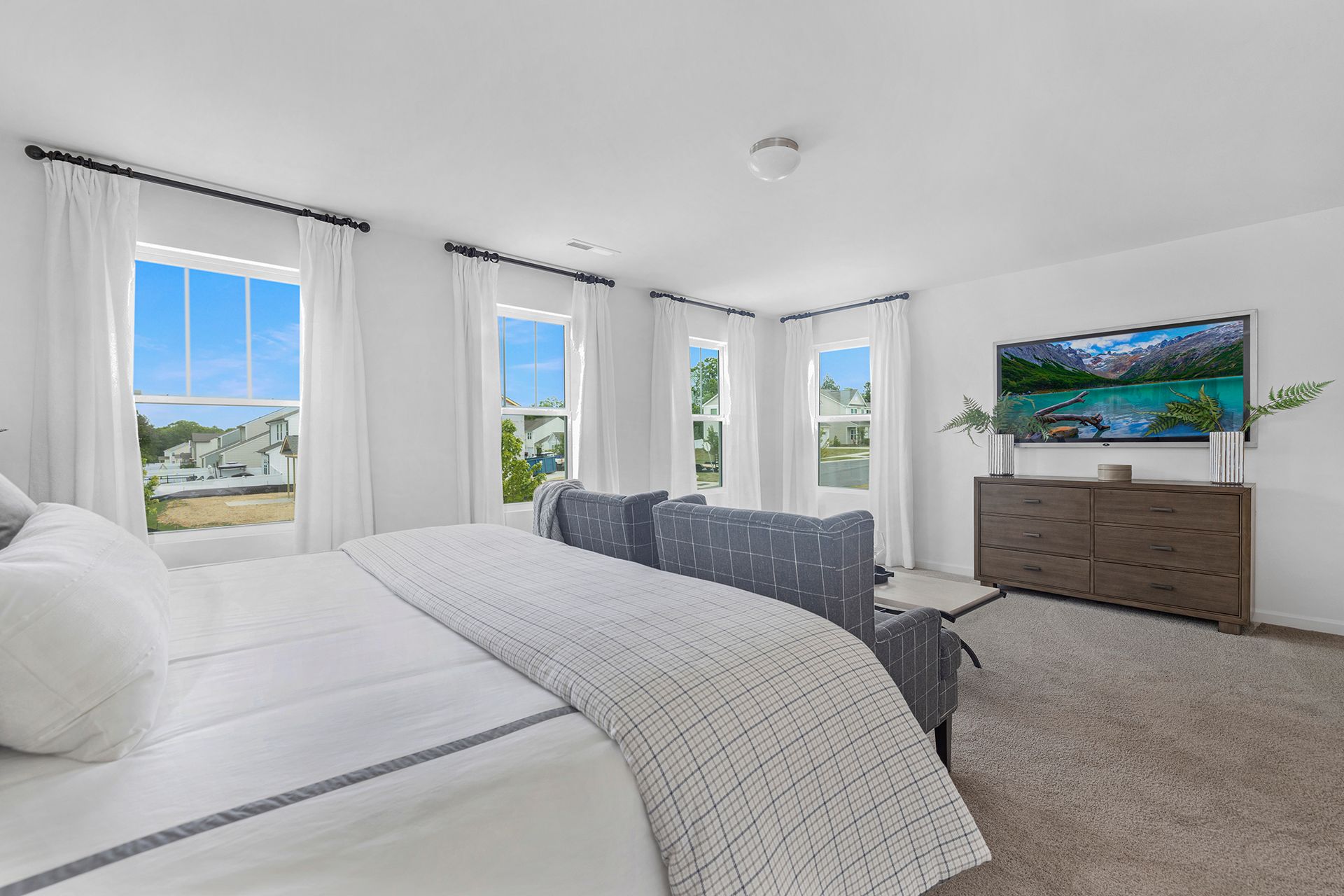 A bedroom with a bed , couch , television and windows.